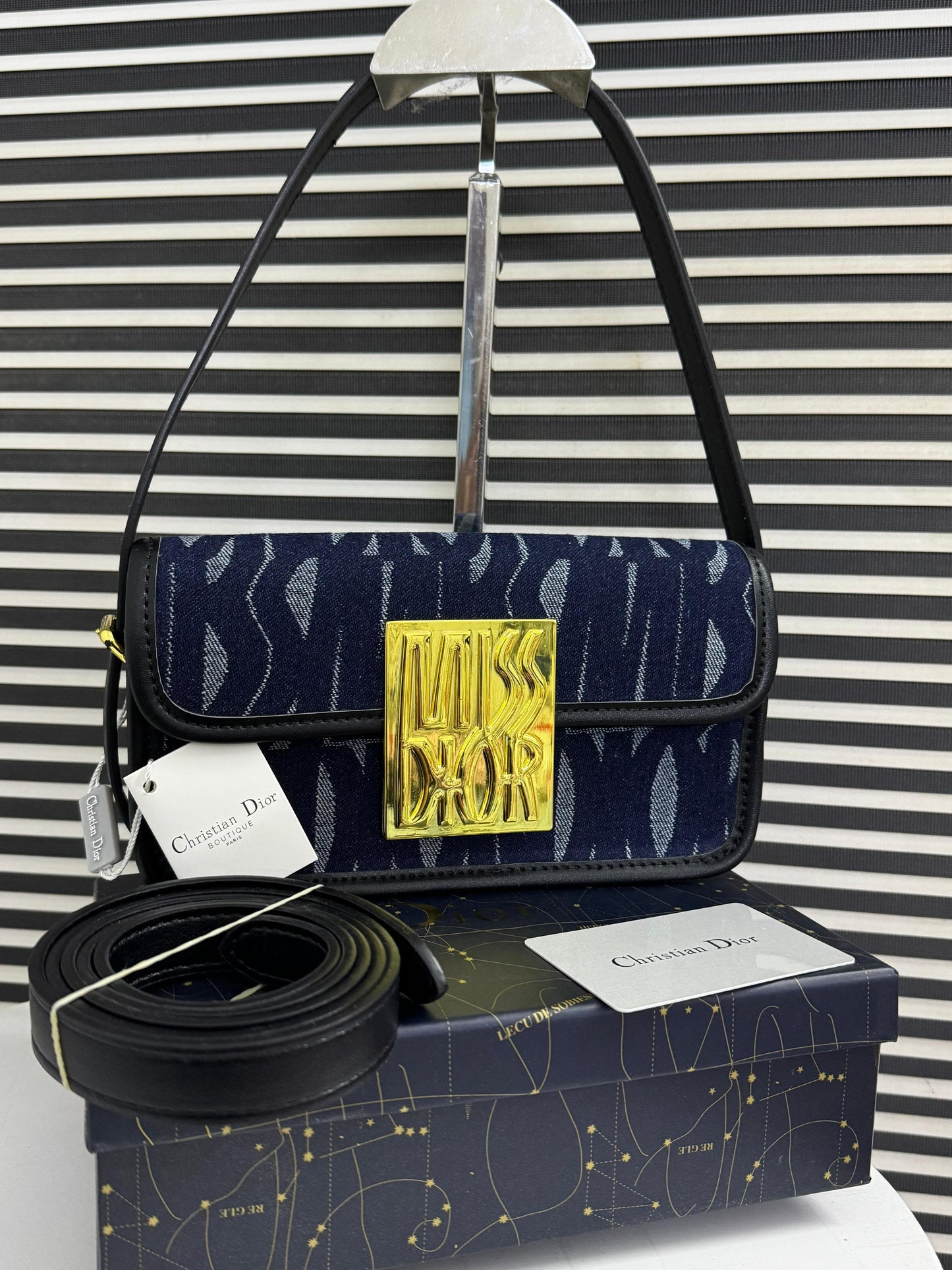 Designer handbag with 'Di or' logo on a striped background