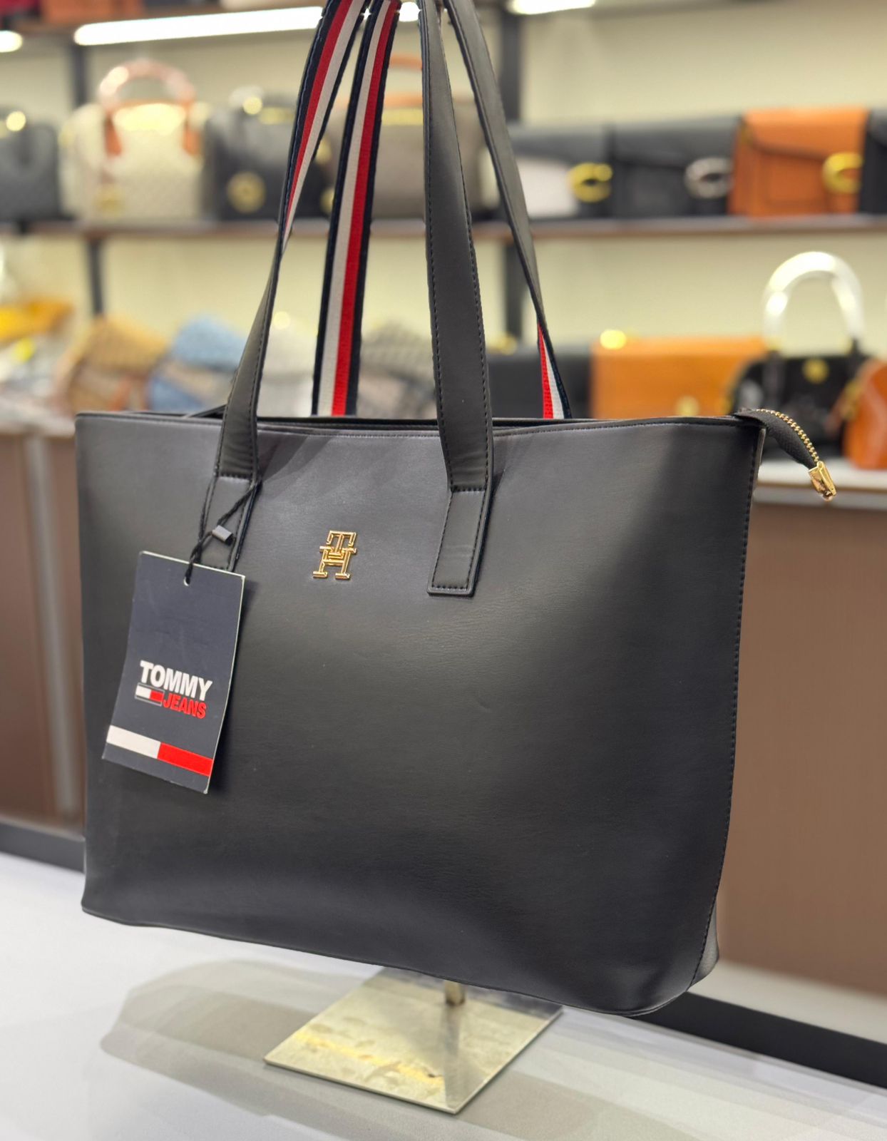 Black handbag with a visible brand tag on a stand in a store setting