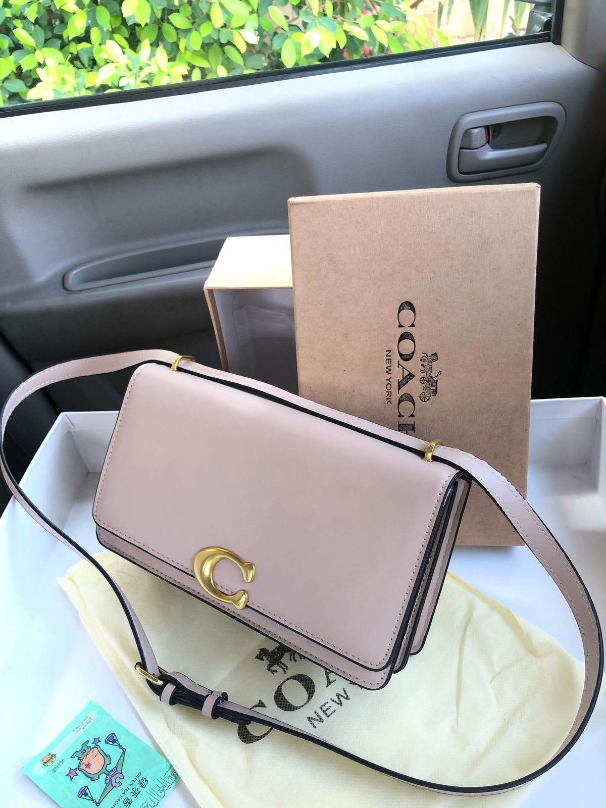 Co ach handbag with a box on a car seat