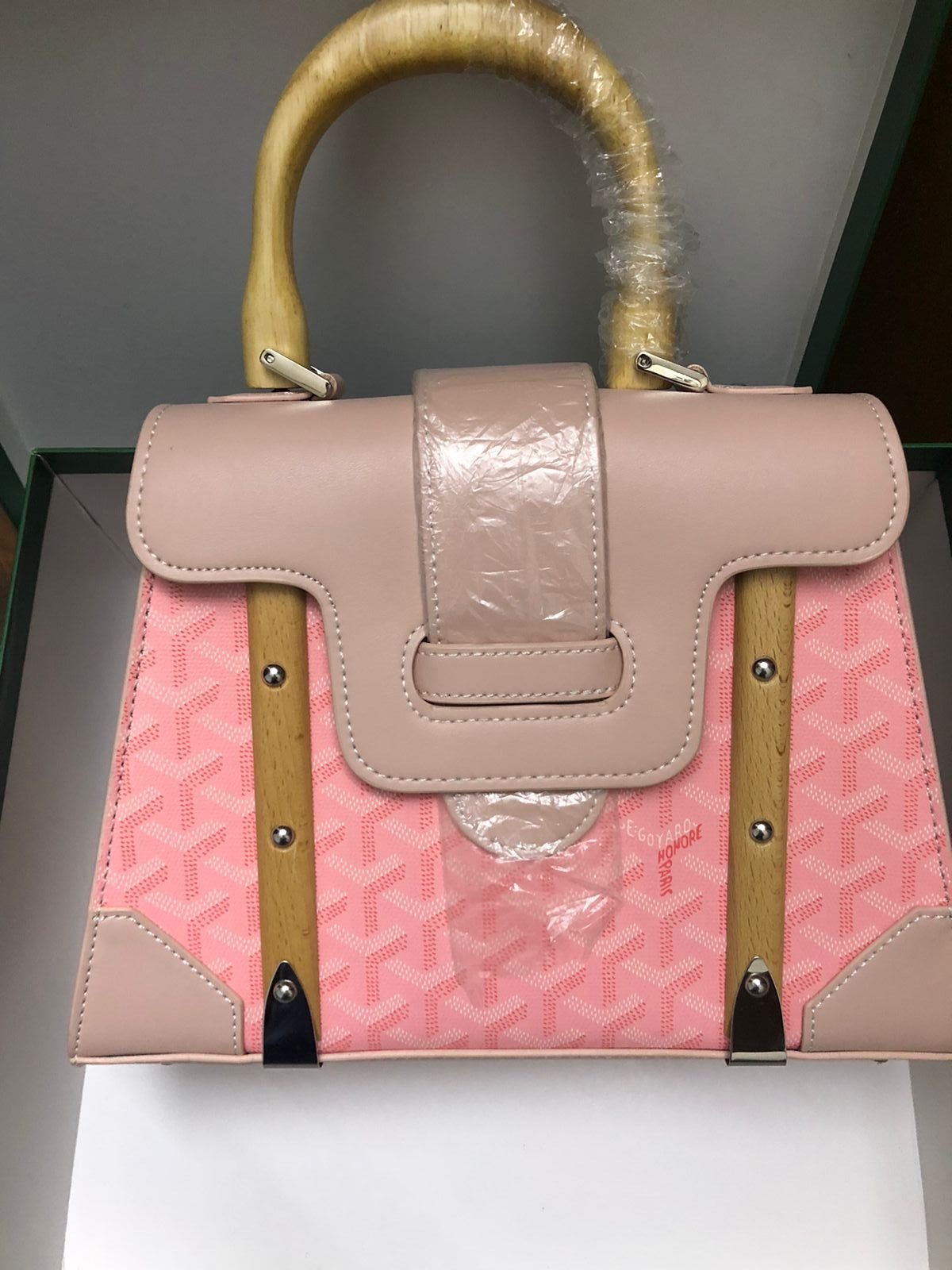 Pink handbag with beige handle and trim on a gray surface