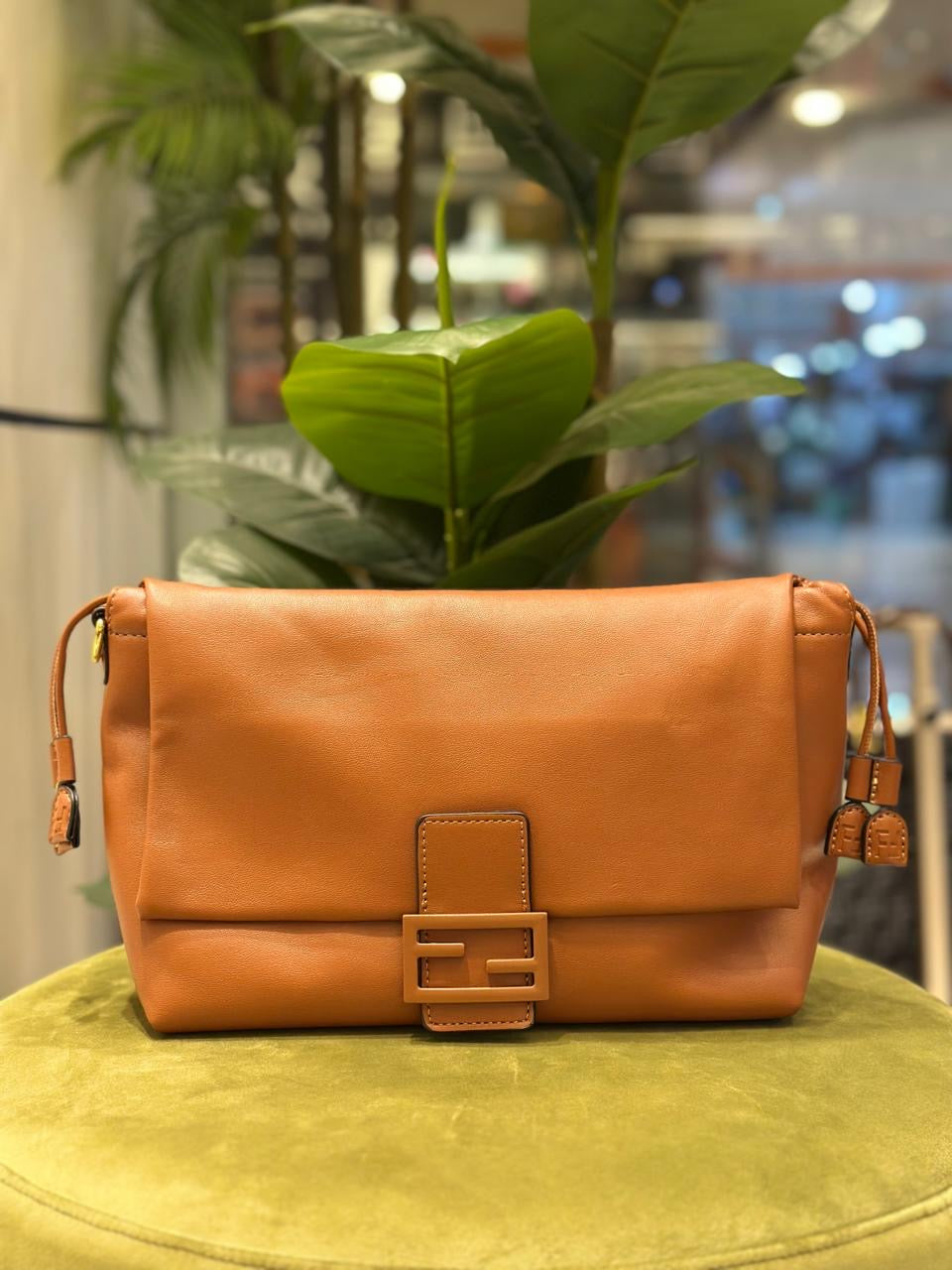 Brown leather handbag on a green surface with a blurred indoor background