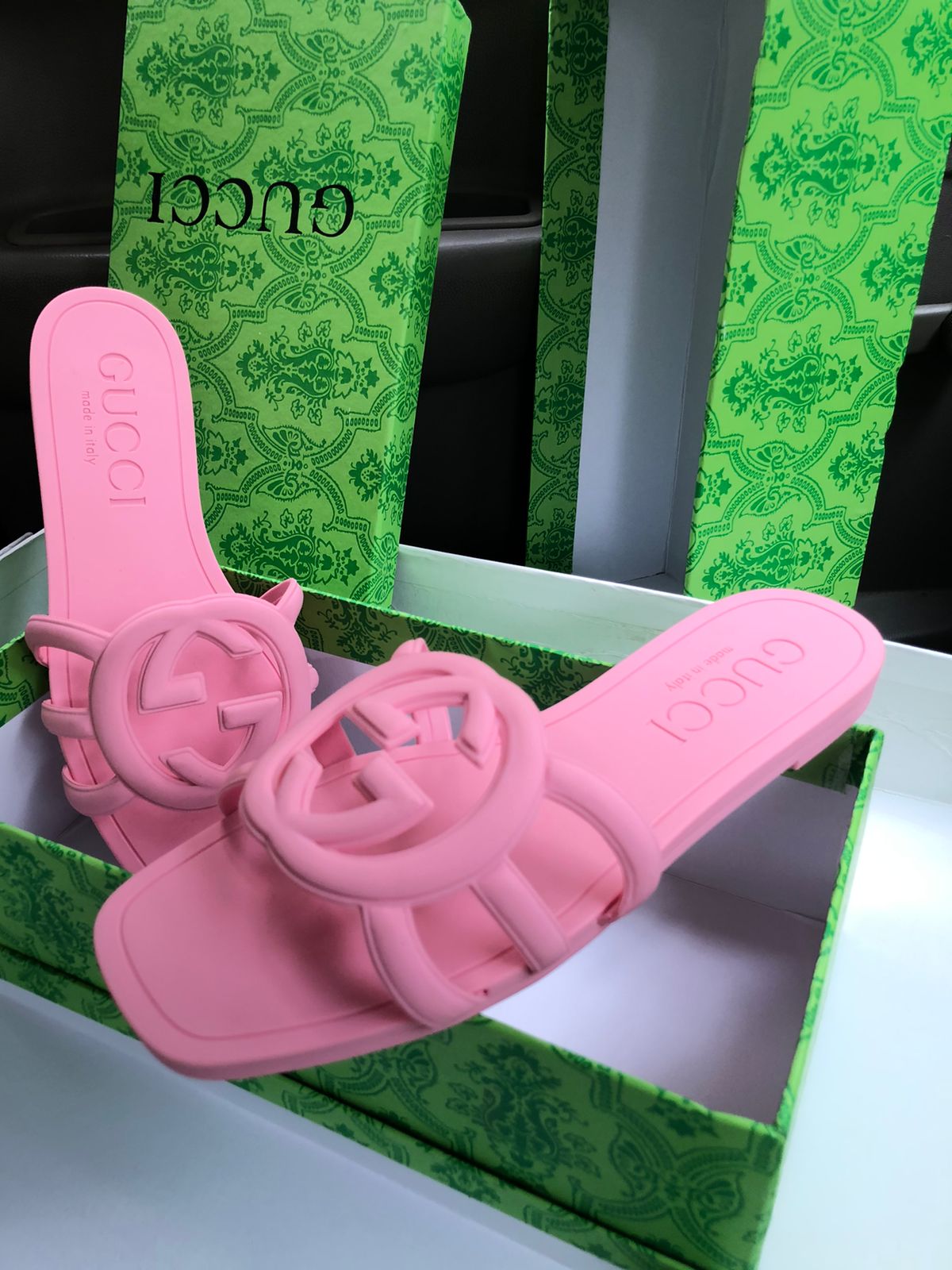 Pink sandals with Guc ci logo on a green box