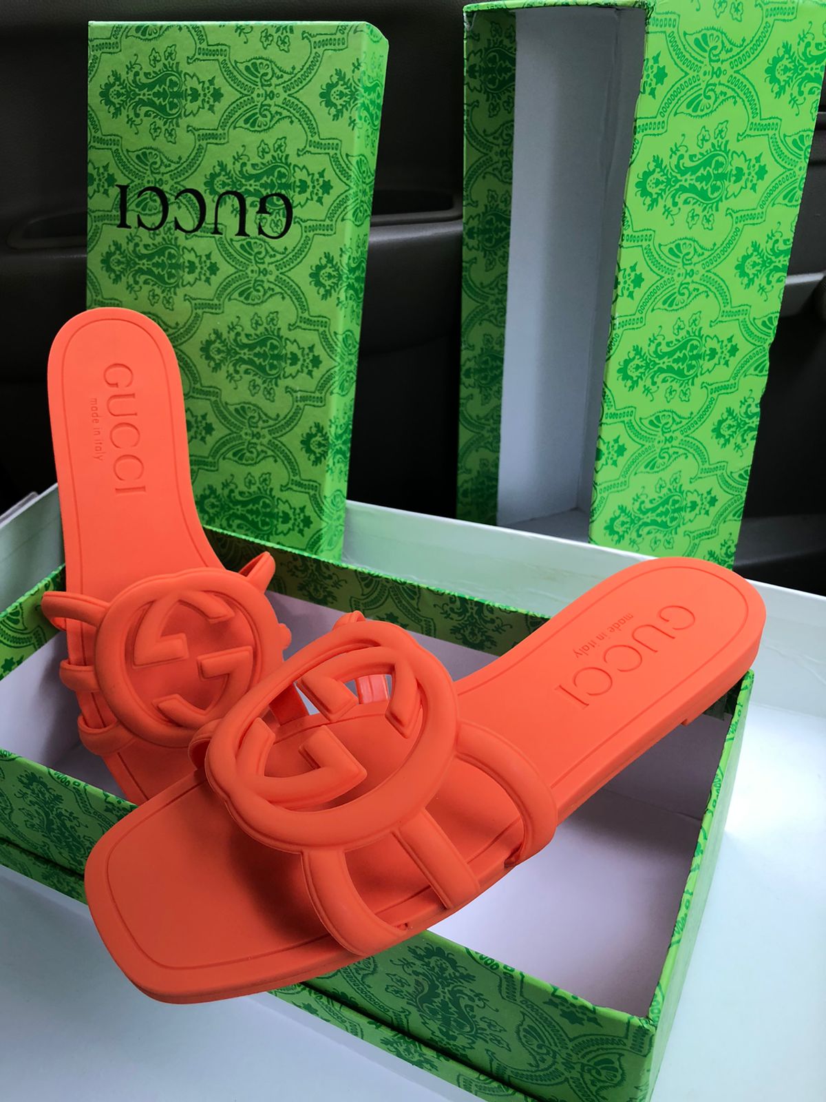Orange sandals with Guc ci branding on a green box