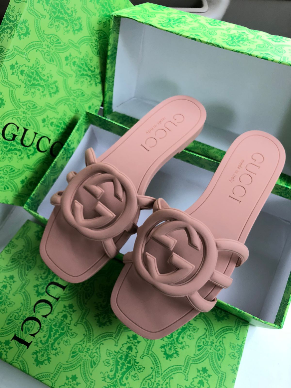 Pink sandals with Guc ci logo on a green Guc ci box