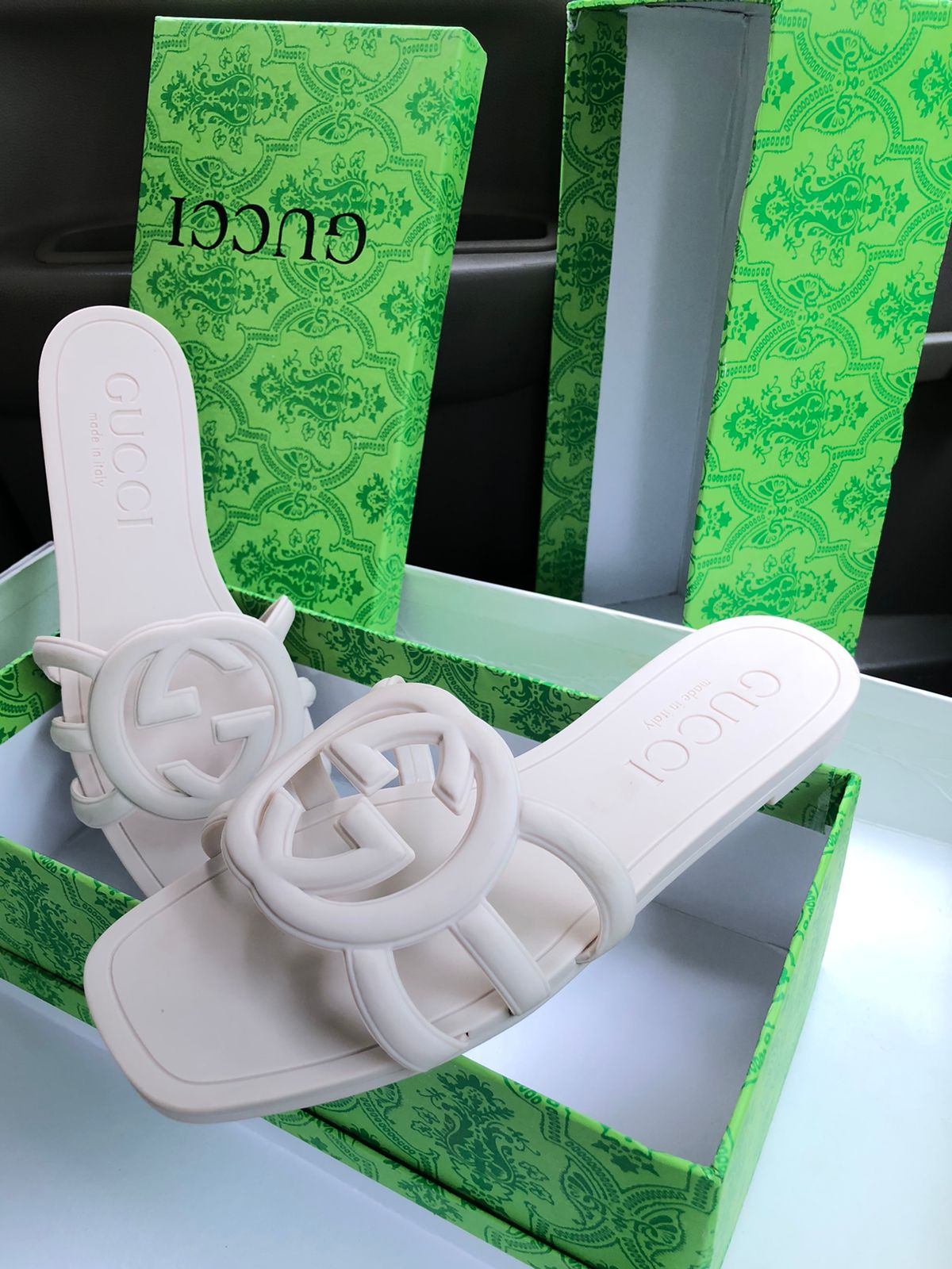 White sandals with a brand logo on a green branded box