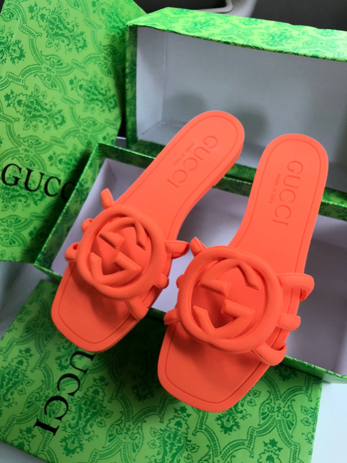 Orange sandals with floral design on a green Guc ci box