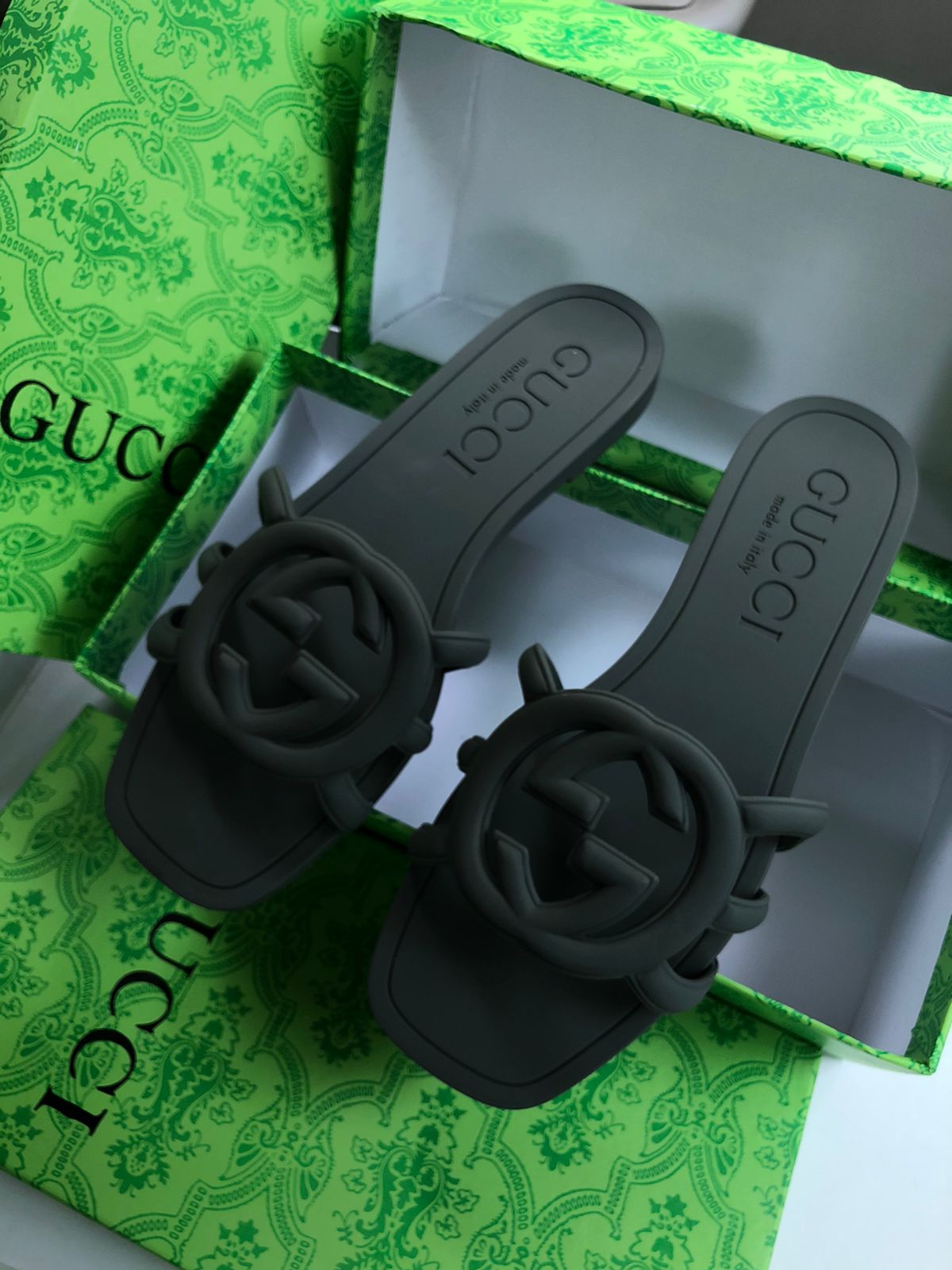 Black sandals with floral designs on a green Guc ci box