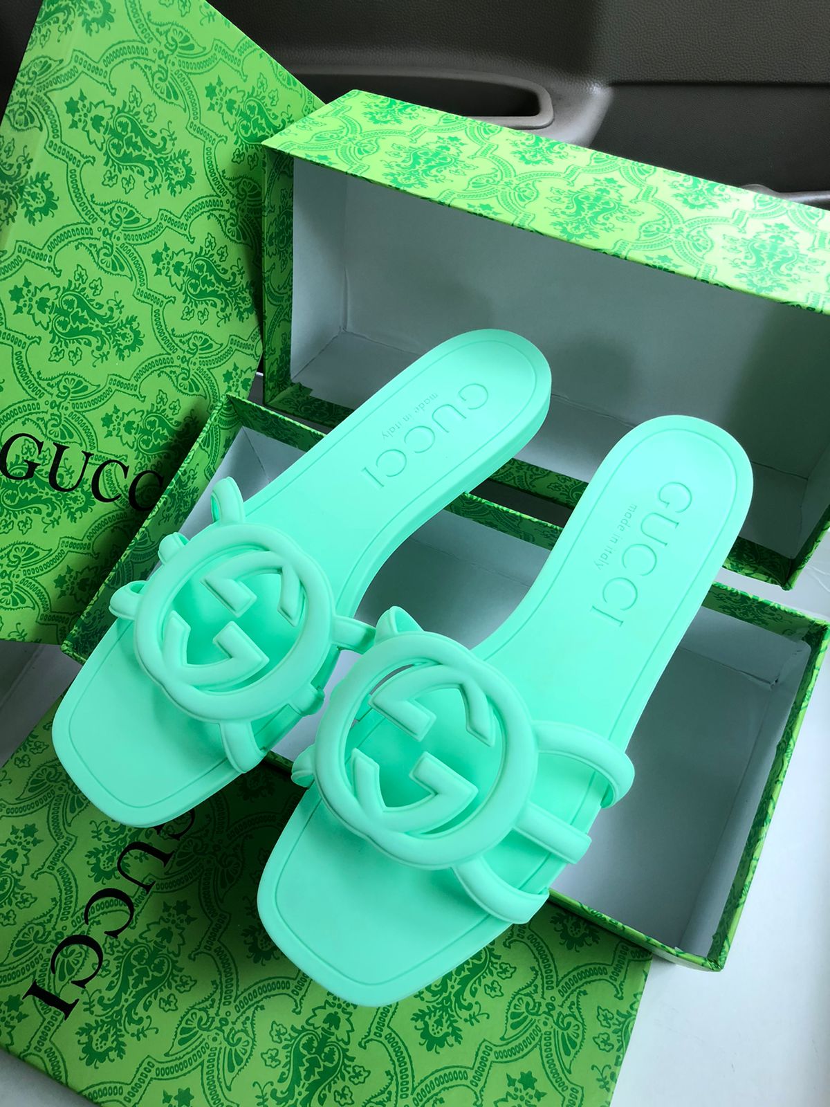Green slide sandals with Guc ci logo on a green Guc ci box