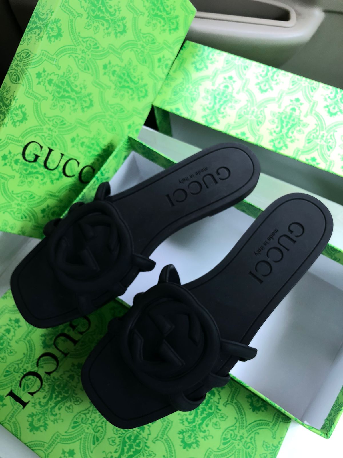 Black sandals with floral designs on a Guc ci box