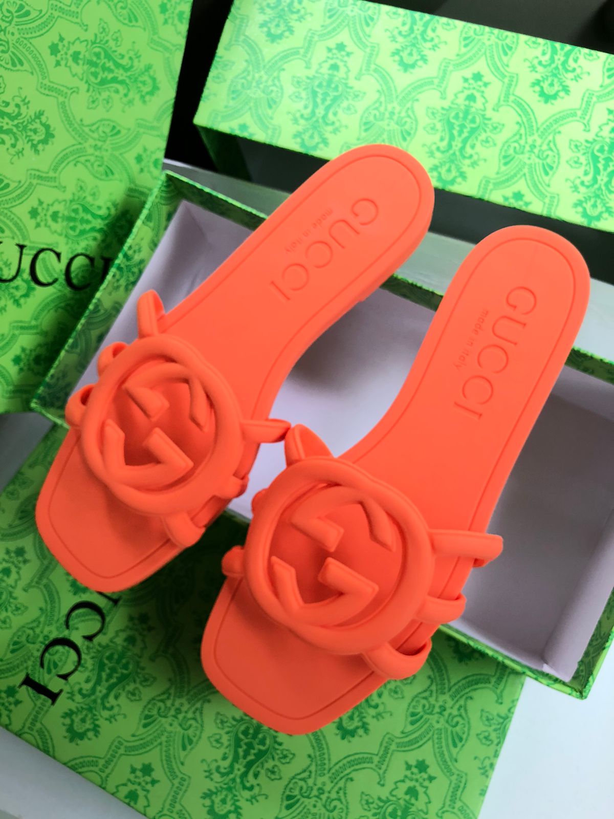 Orange sandals with floral designs on a green patterned surface