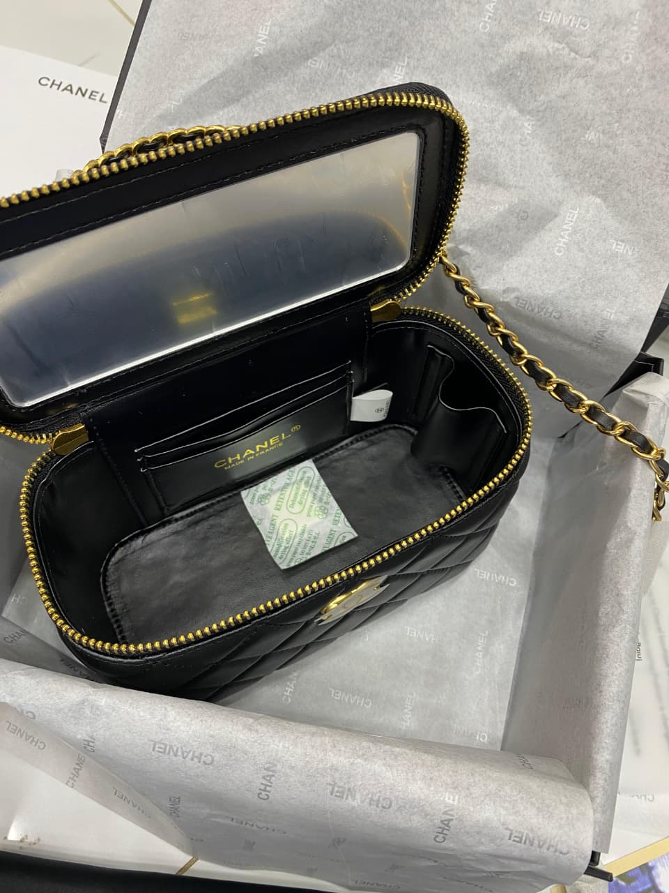 Black handbag with gold zipper on a gray background