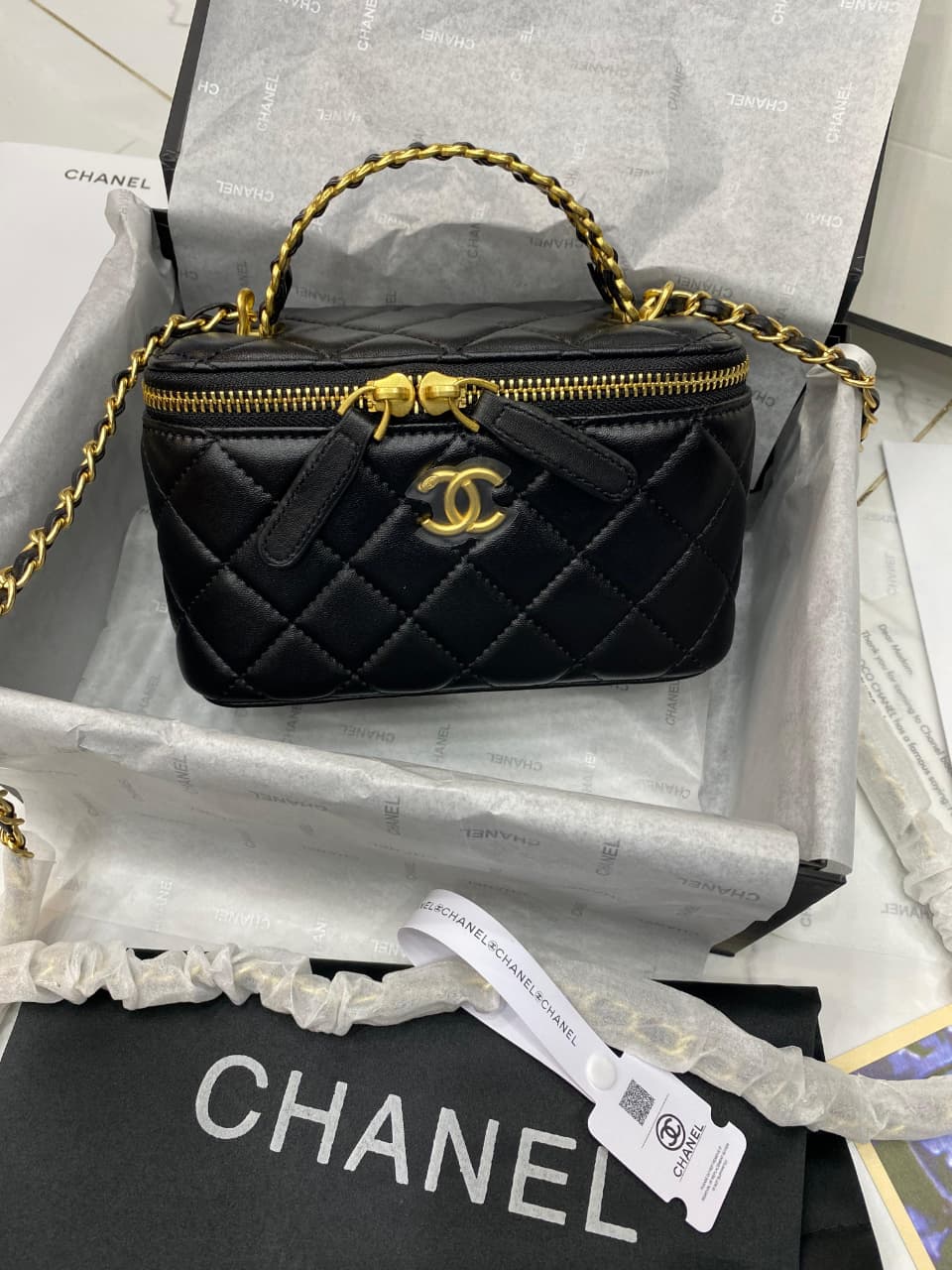 Black quilted handbag with gold accents on a Cha nel box