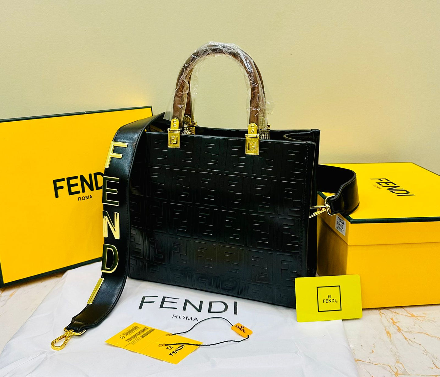 Black Fen di handbag with yellow tags and packaging on a light background