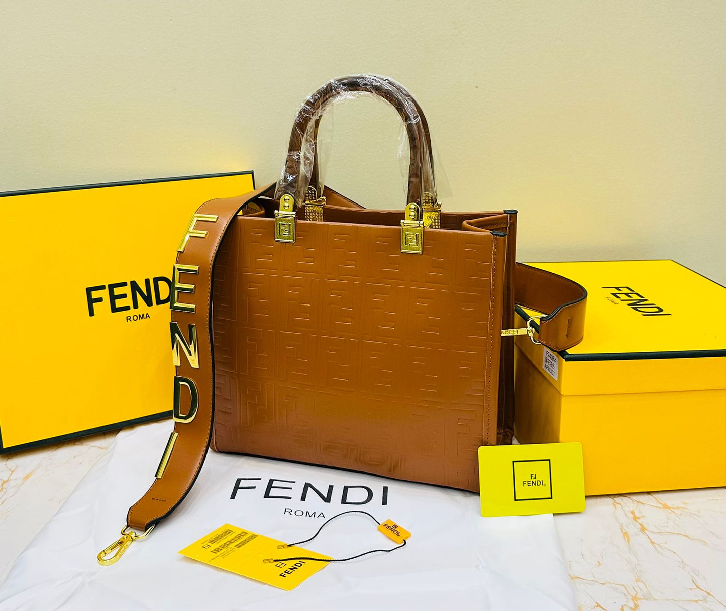 Fen di handbag with yellow strap and packaging on a light background