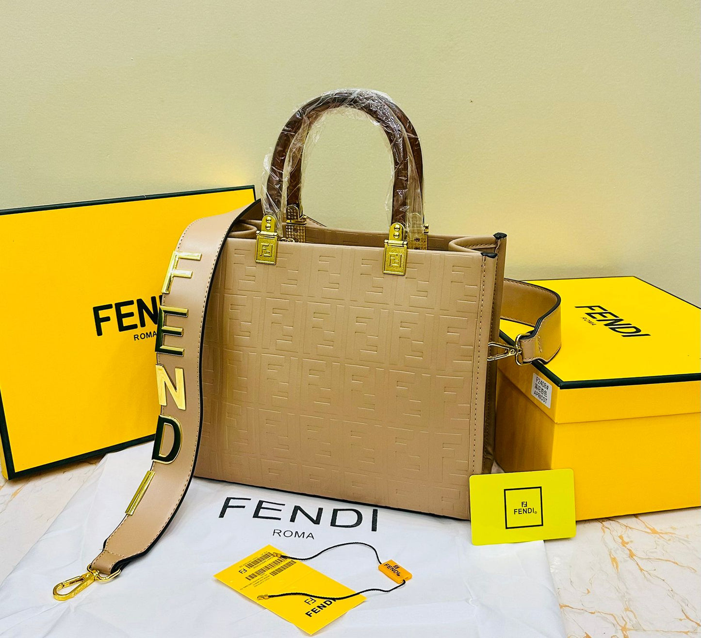 Fen di handbag with yellow straps and packaging on a light background