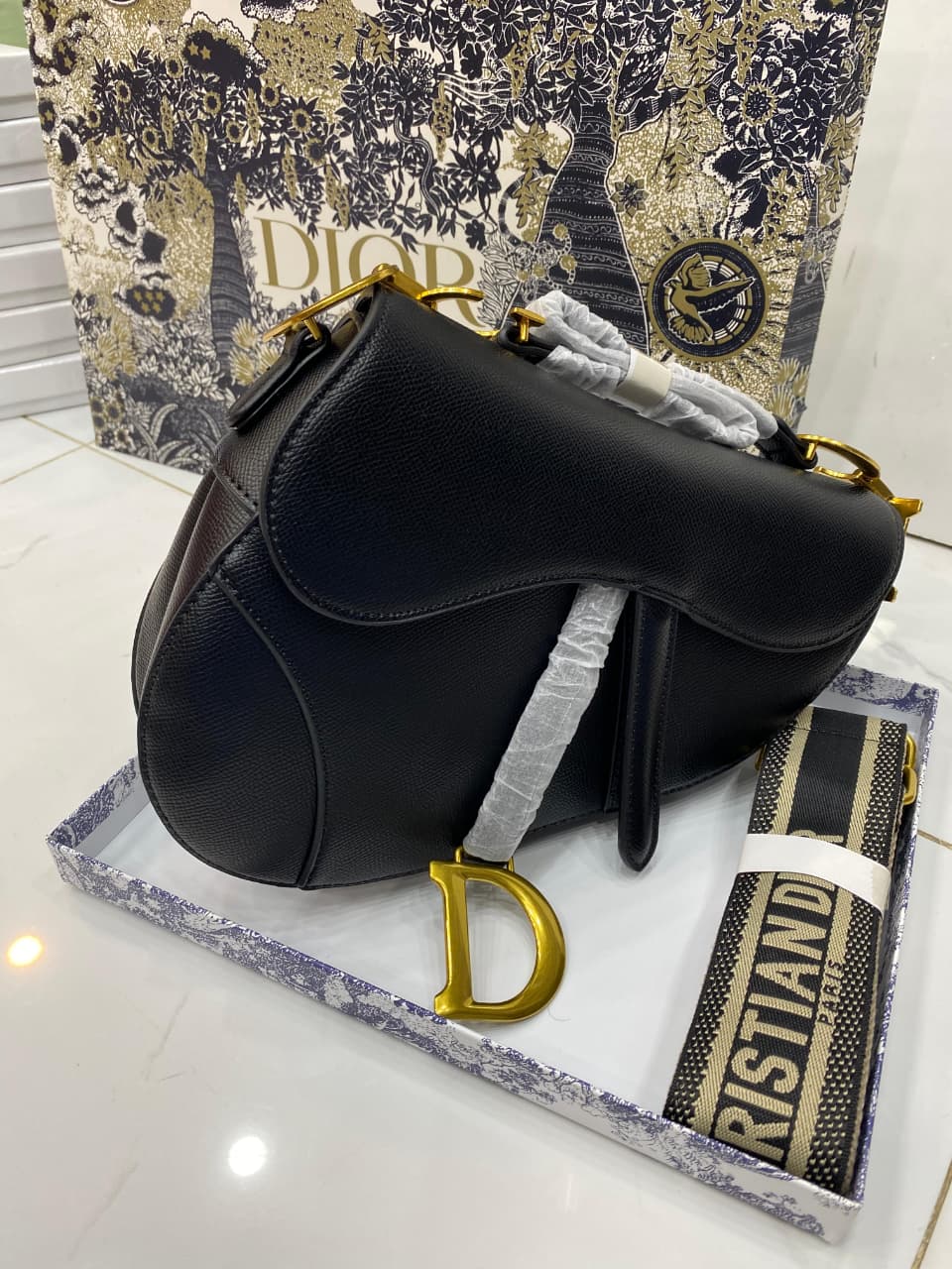 Black handbag with gold accents on a branded surface