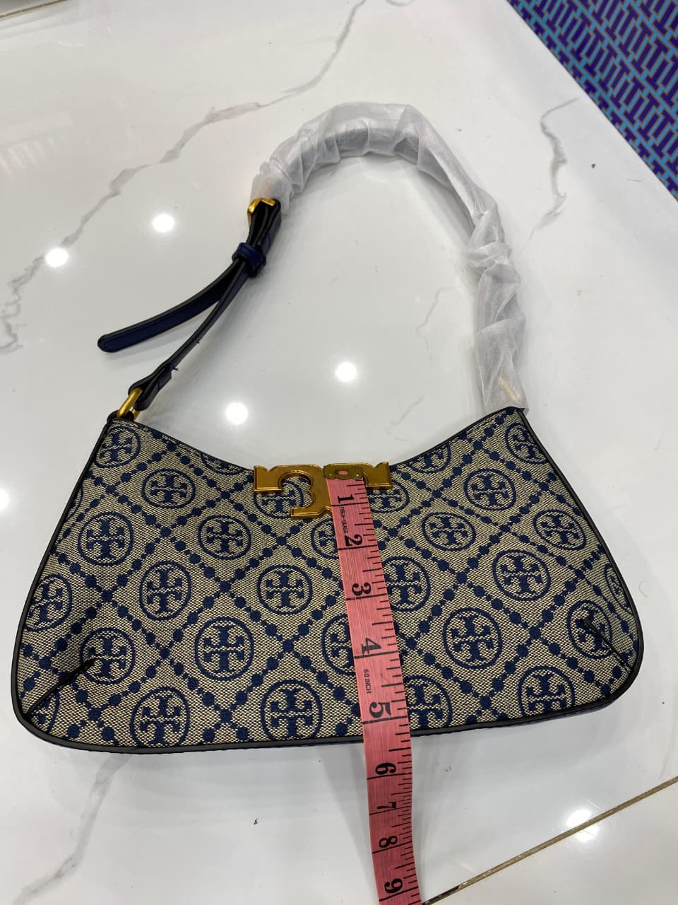 Handbag with a pattern and a measuring tape for scale on a white surface