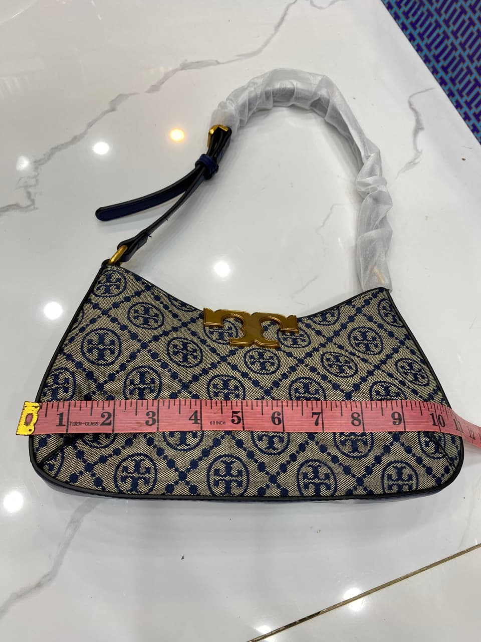 Handbag with a pattern and a measuring tape for scale on a white surface