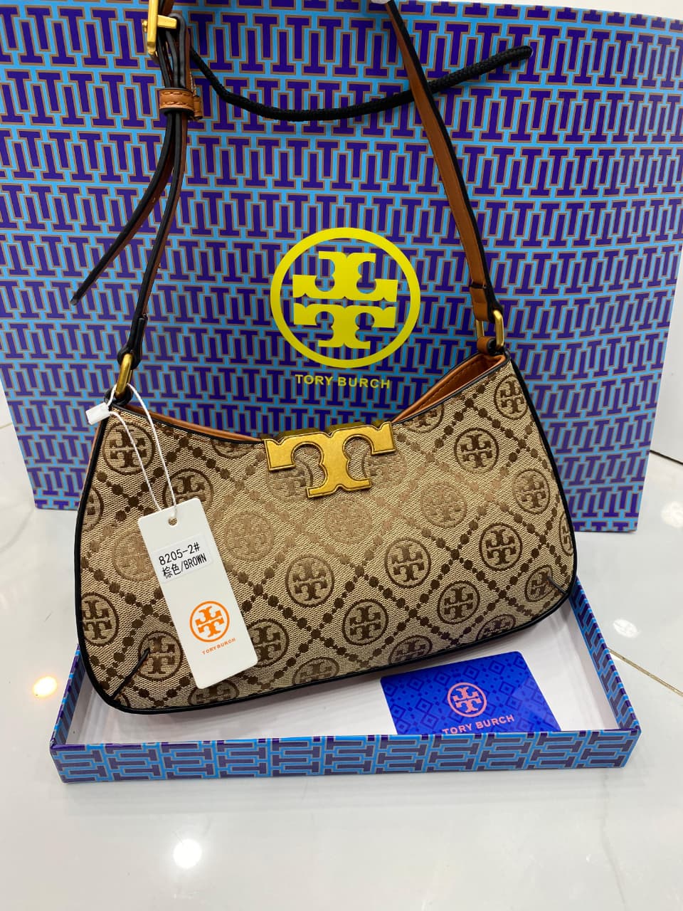 To ry Bur ch handbag with a tag in front of a branded box