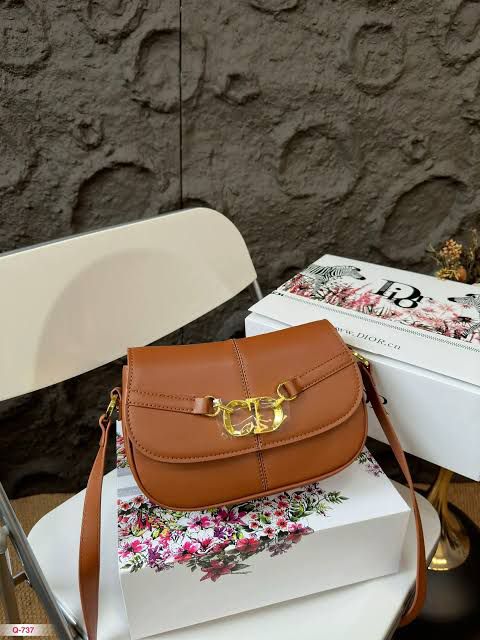 Brown handbag with gold clasp on a floral-patterned box against a textured wall.