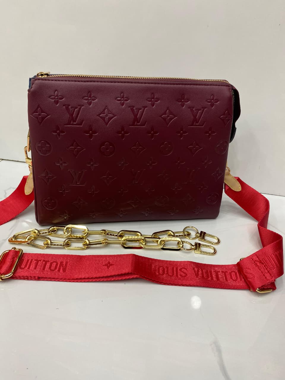 Red handbag with gold chain strap on a white background