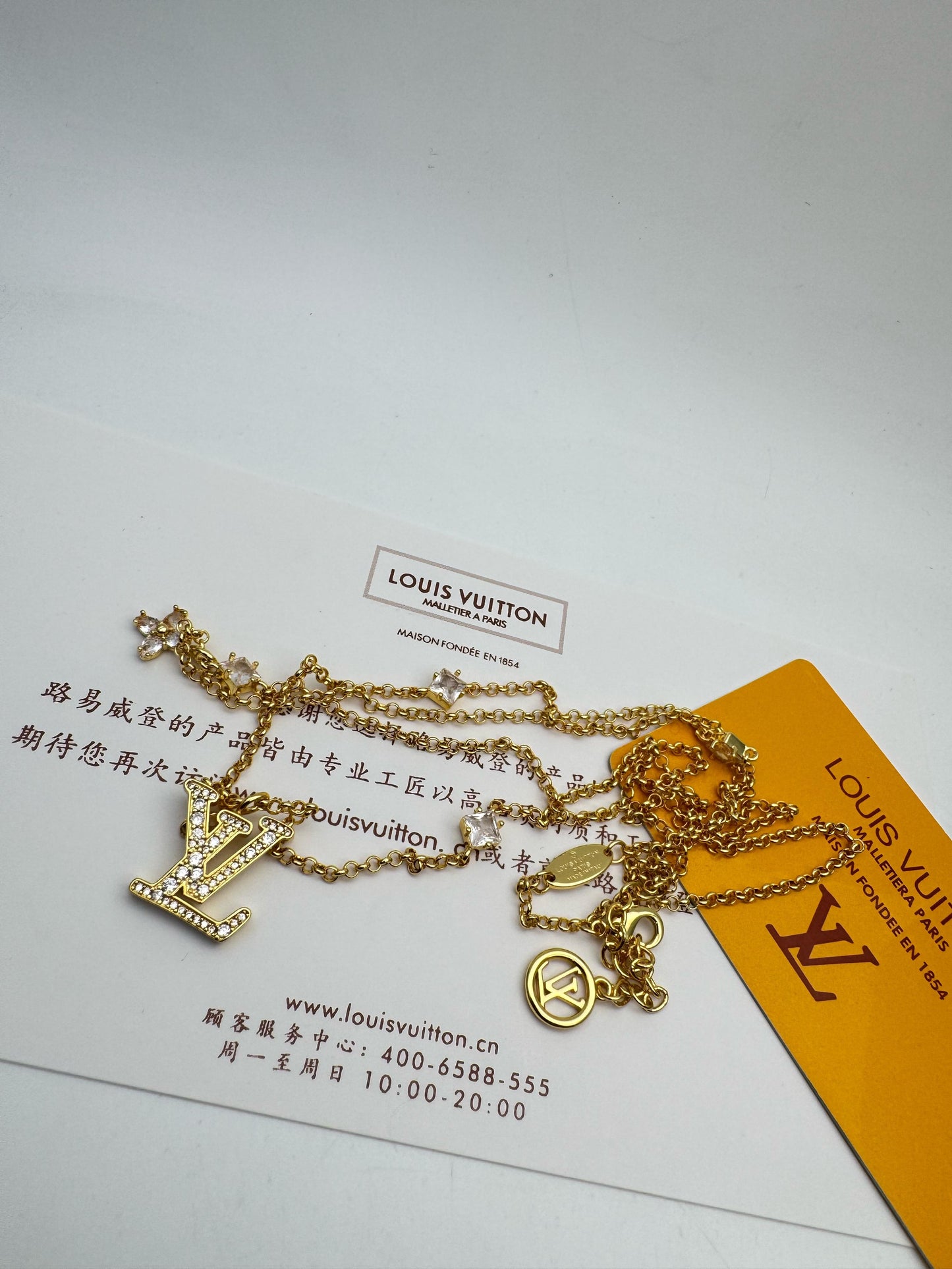 Gold necklace with 'Lo-uis Vuit-ton' tag on a white background