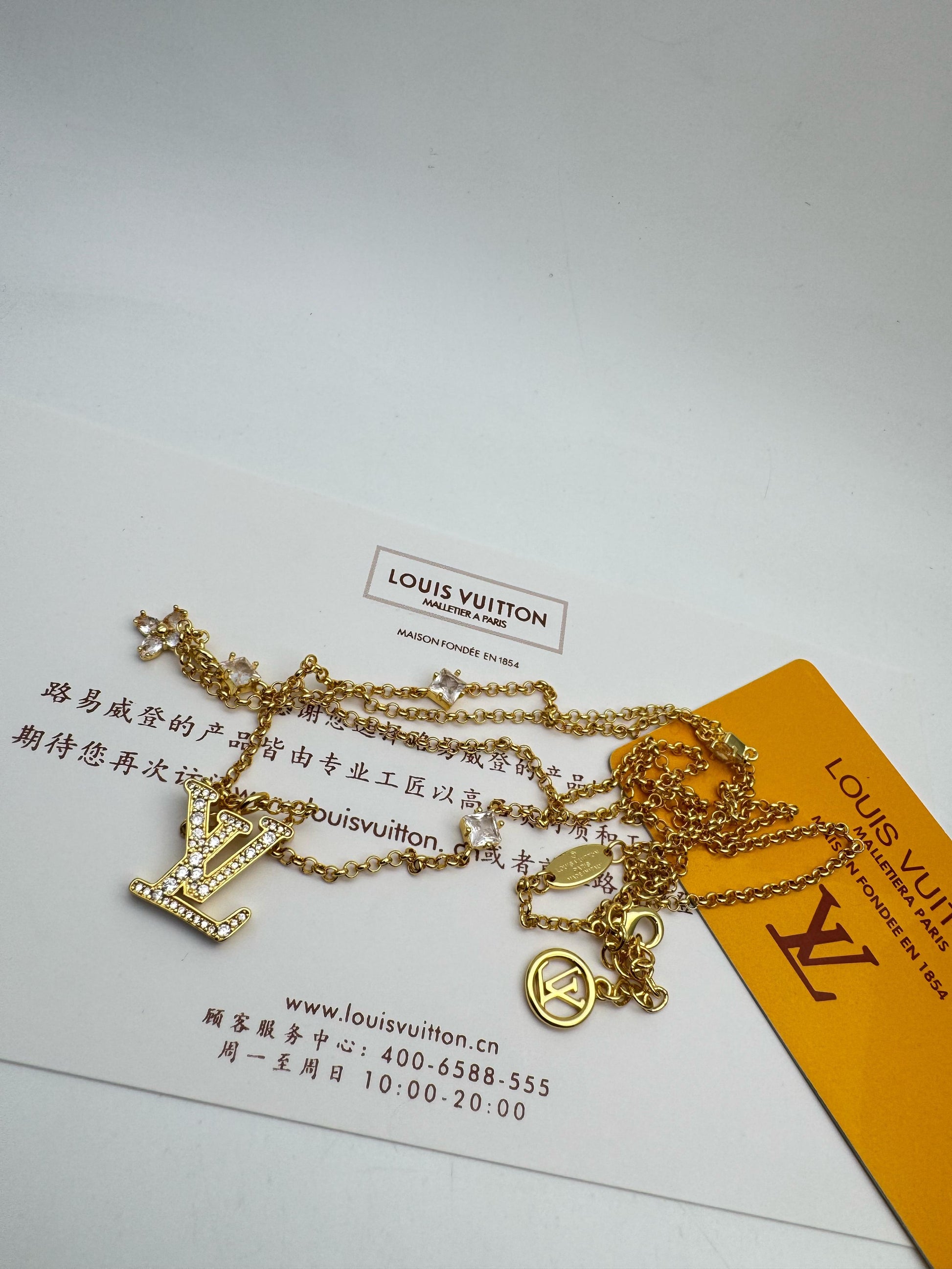 Gold necklace with 'Lo-uis Vuit-ton' tag on a white background