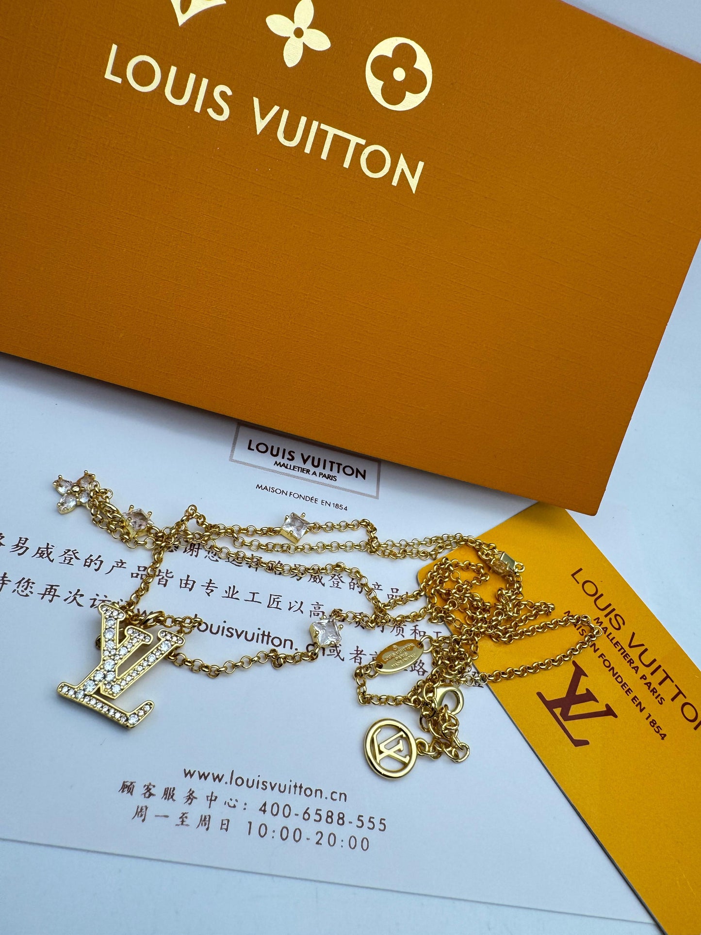 Gold necklace on Lou-is Vui-tton packaging with brand logo.