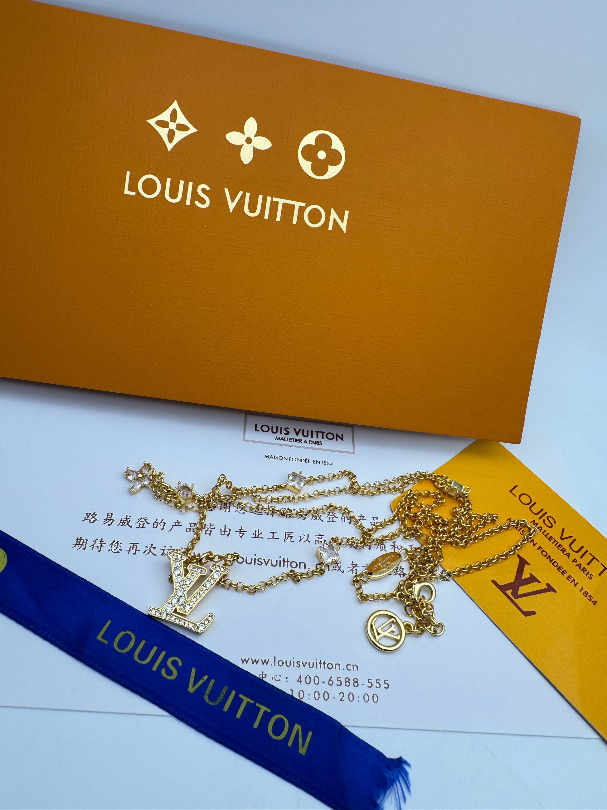 Lou is Vui tton jewelry with packaging on a light blue background