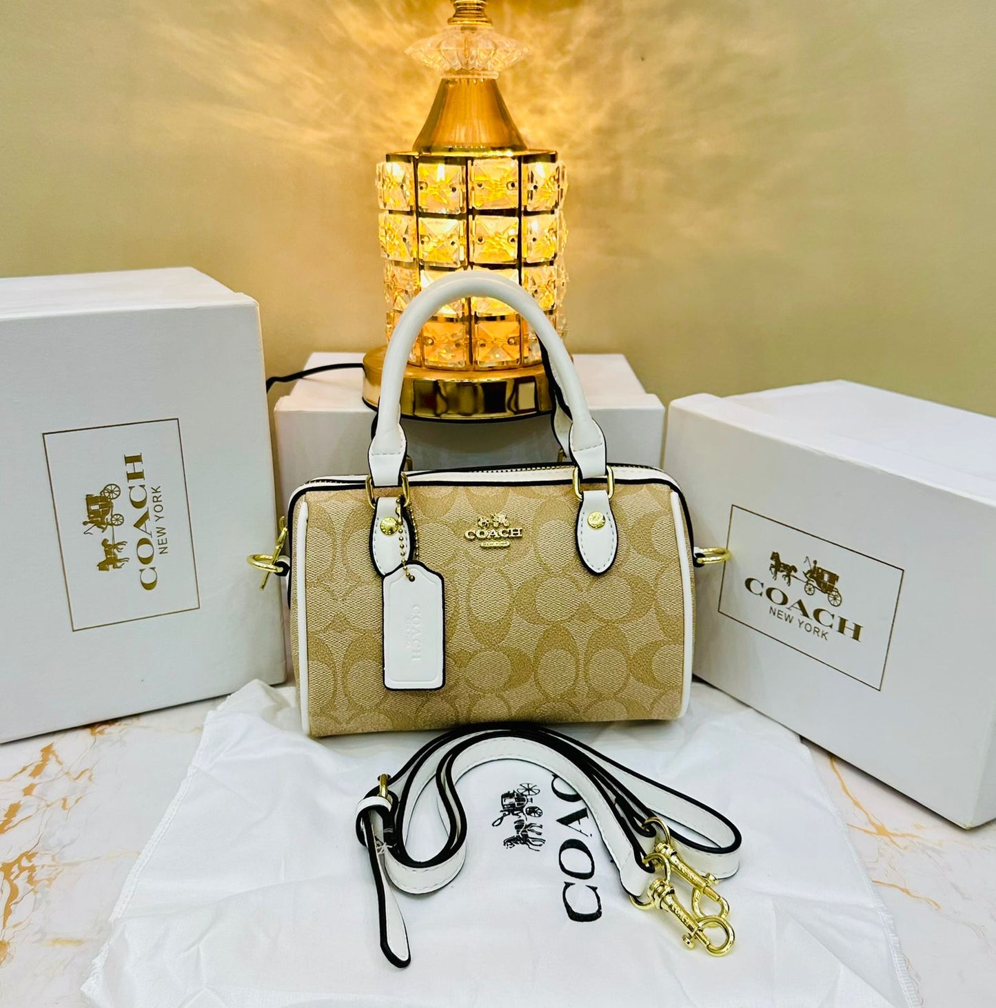 Co ach handbag with matching strap and white box on a decorative surface