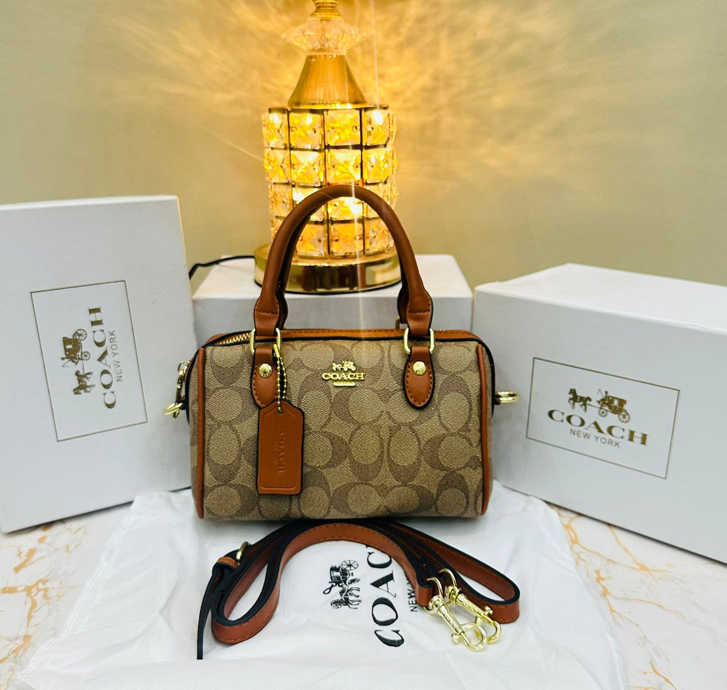 Co ach handbag with matching strap and gold hardware on a white surface with Co ach branding.
