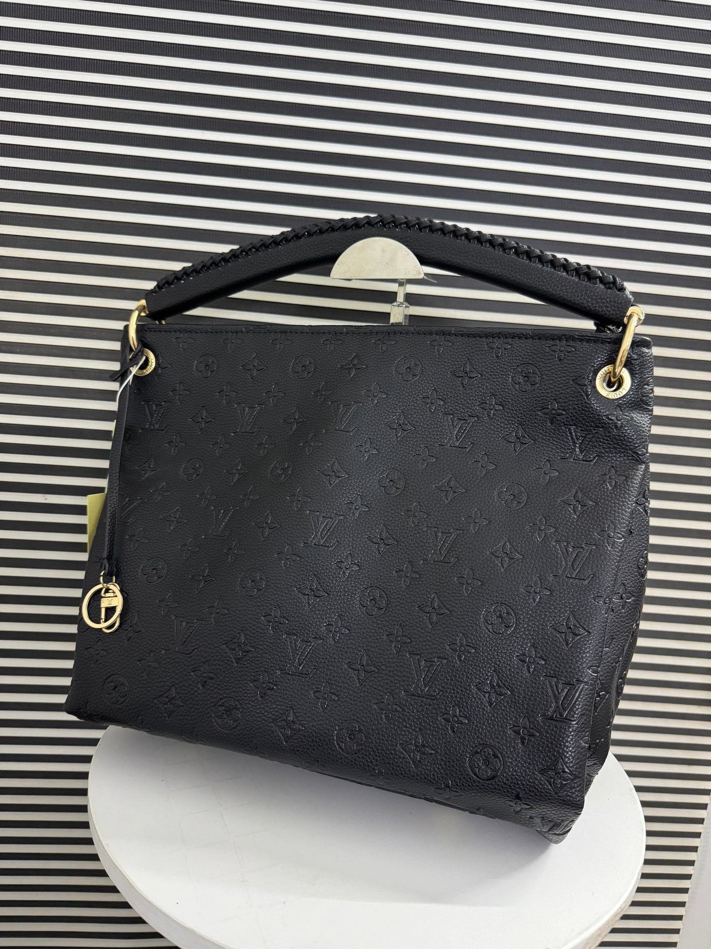 Black handbag with gold accents on a striped background