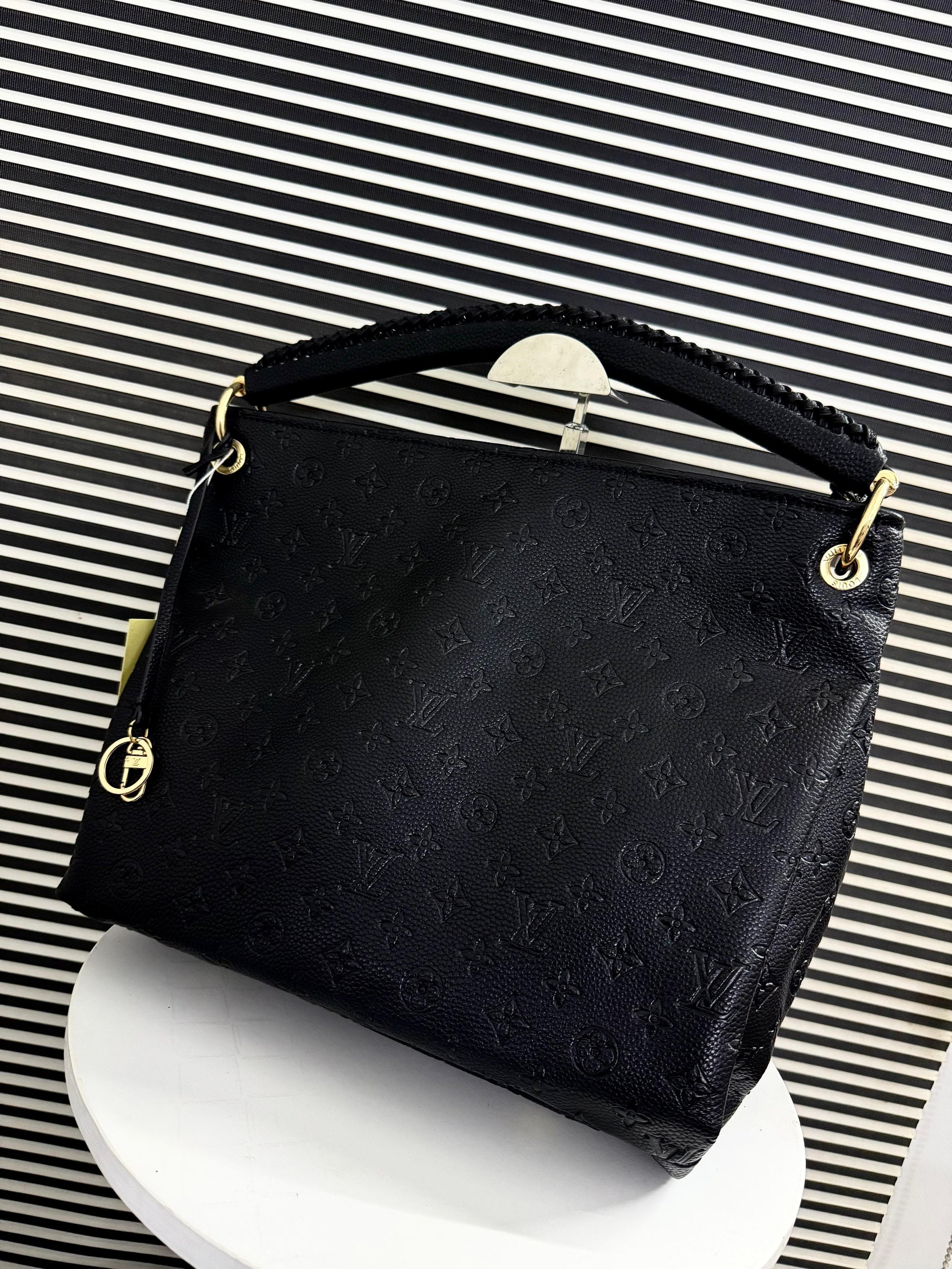 Black handbag with gold accents on a striped background