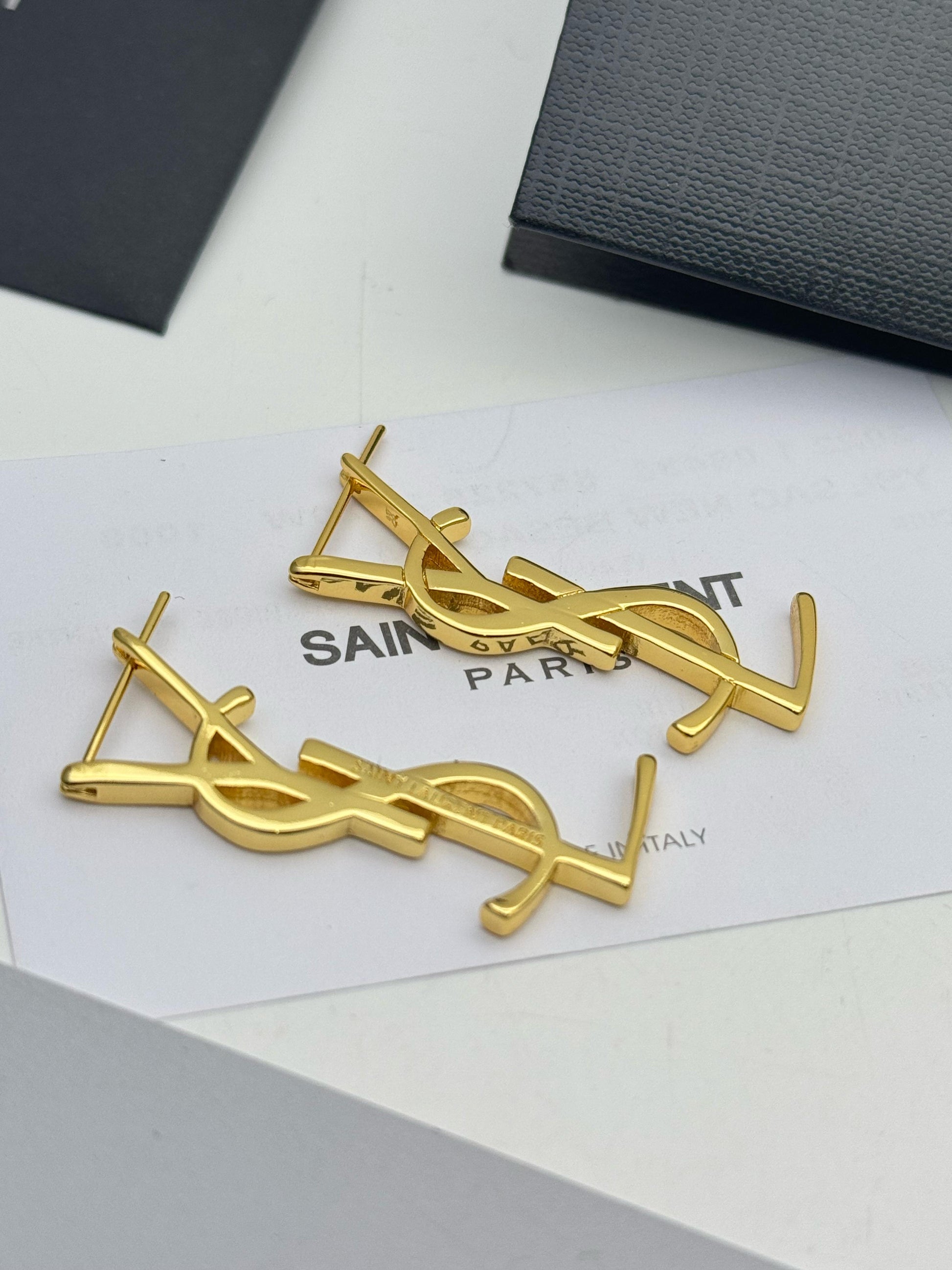 Gold Y S L earrings on a Sa int Lau rent branded card