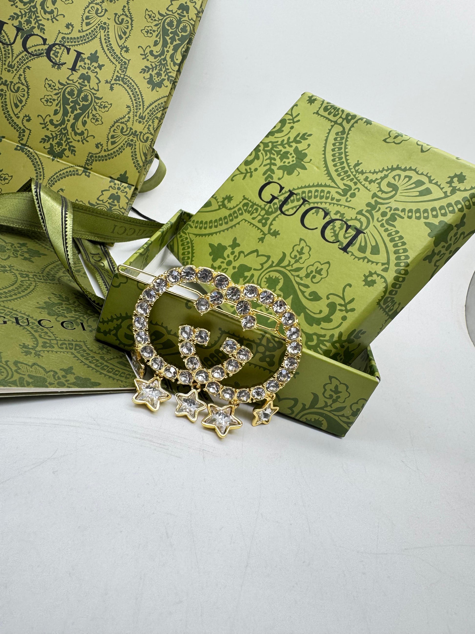 Guc ci brooch with stars on a green Gu cci box
