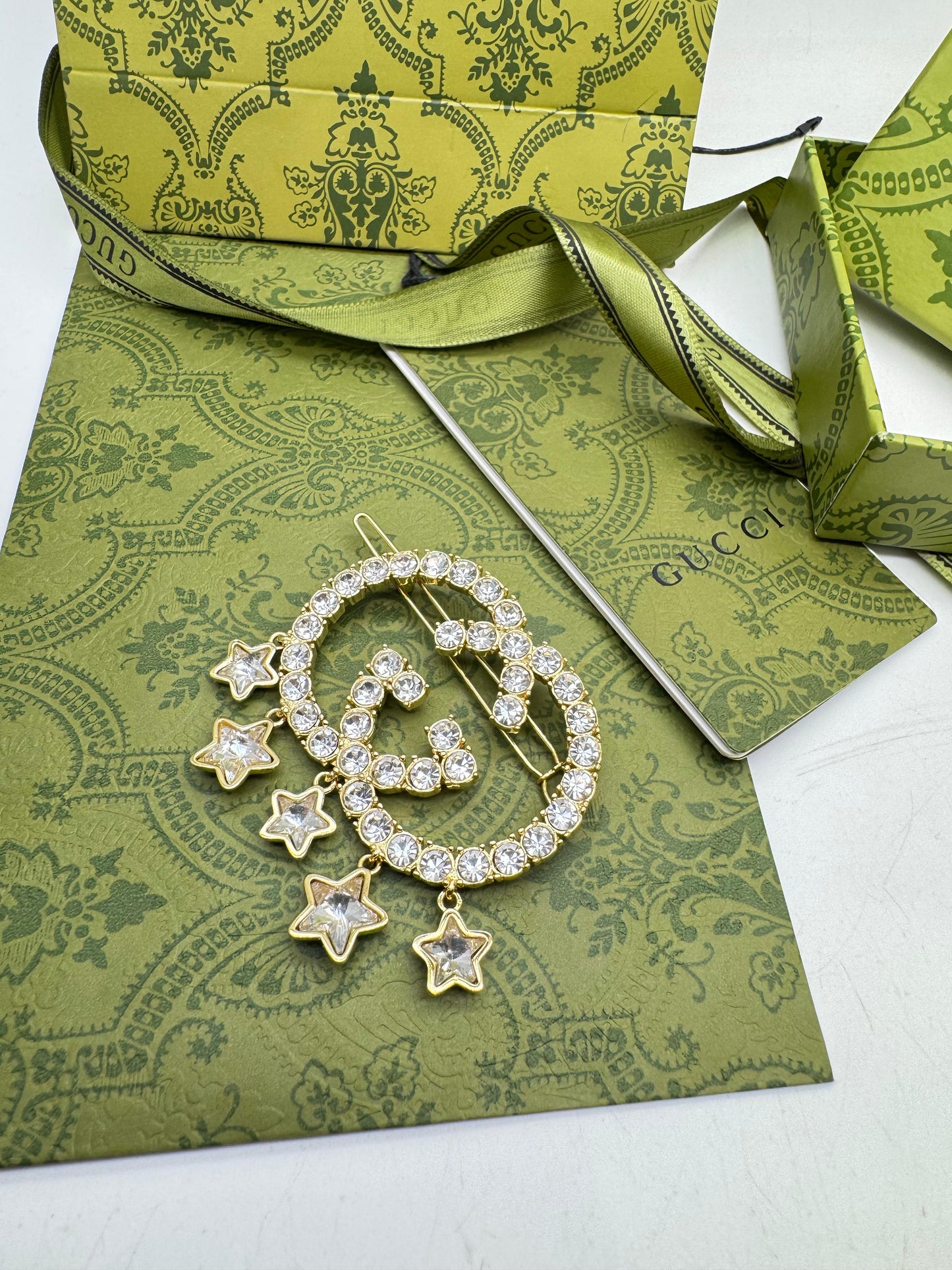 Gold brooch with star designs on a green patterned card