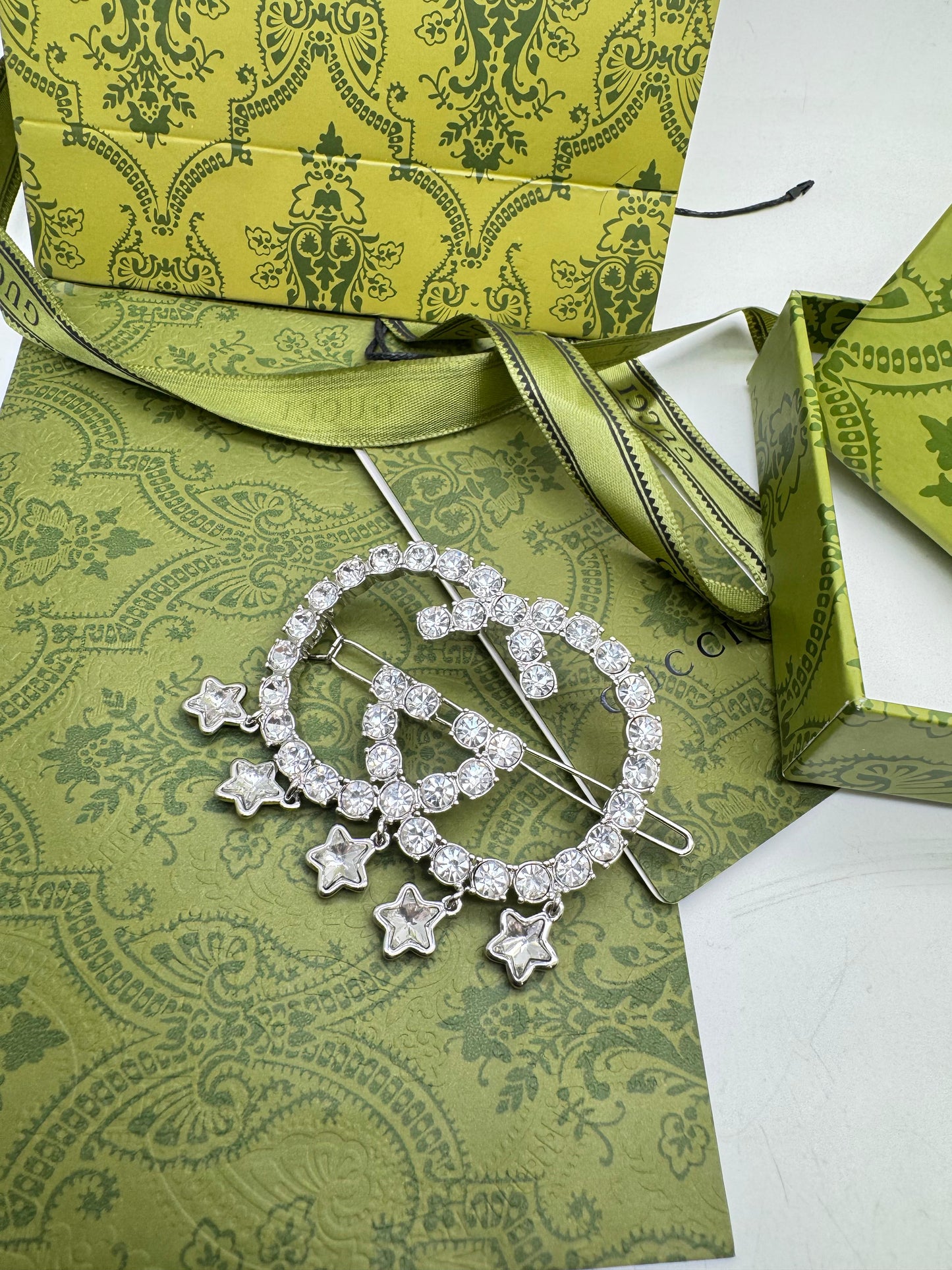 Silver brooch with star charms on a green patterned surface