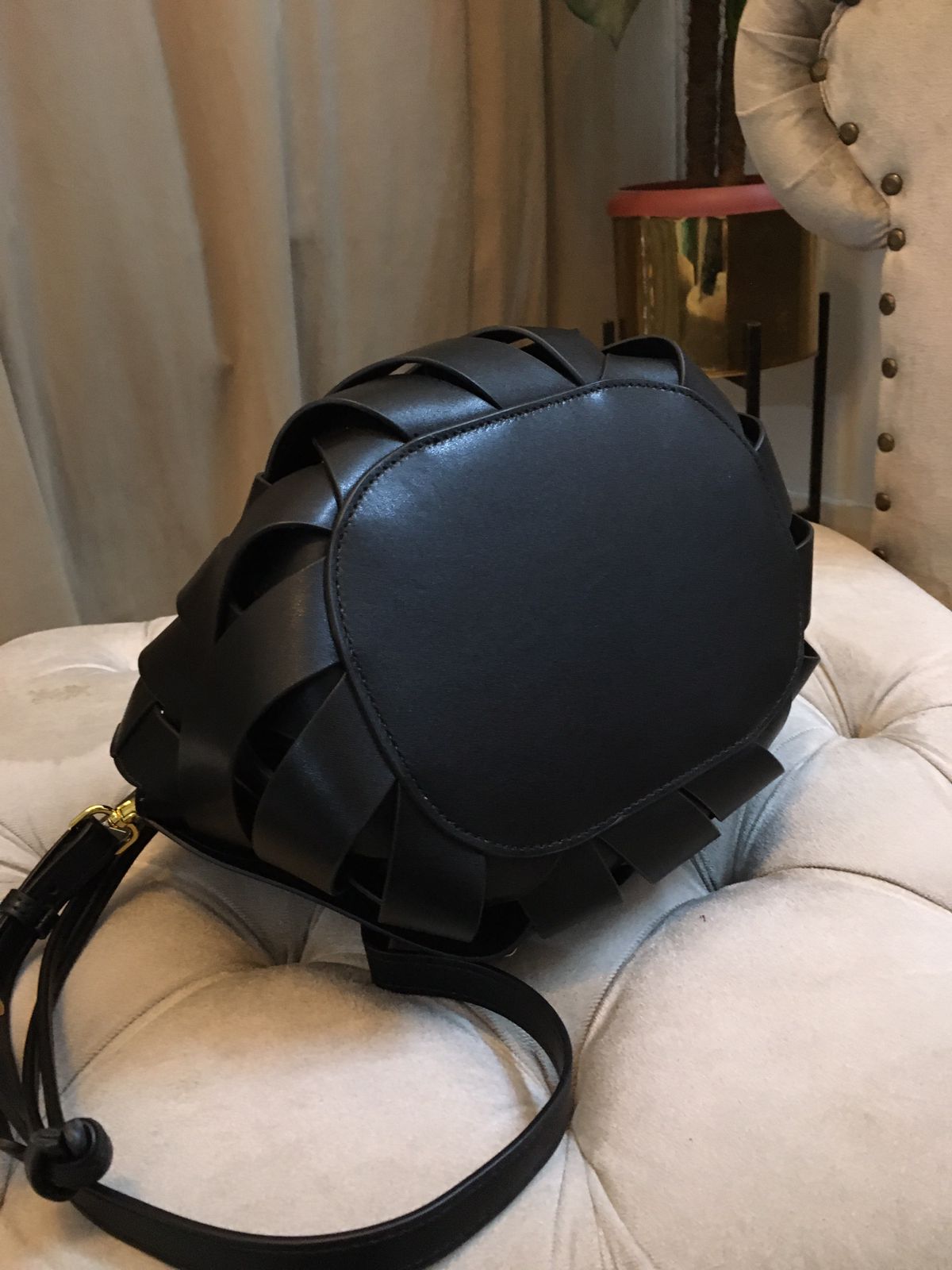 Black leather backpack on a beige cushioned chair