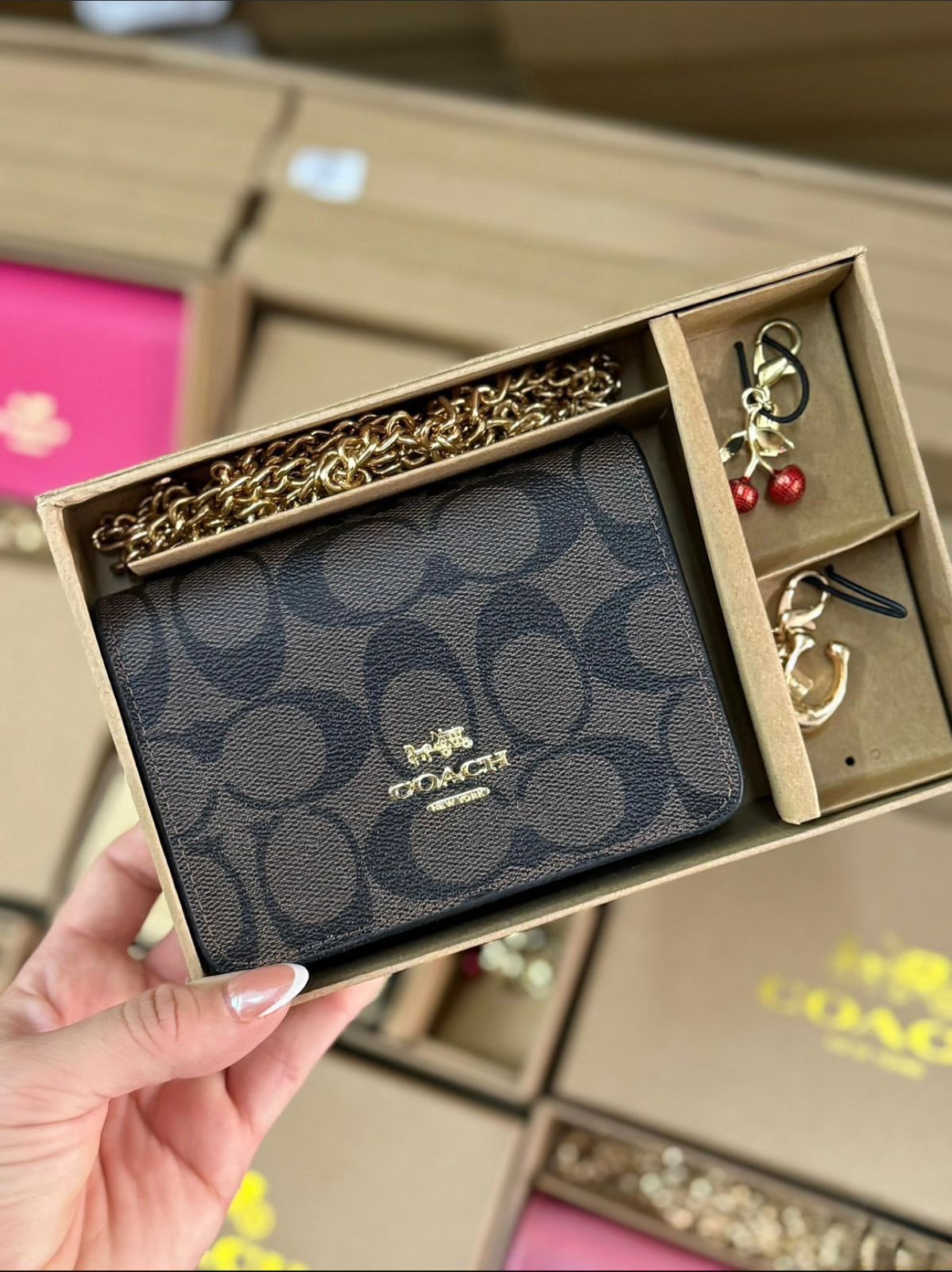 Coa ch wallet and keychain set in a box held by a hand