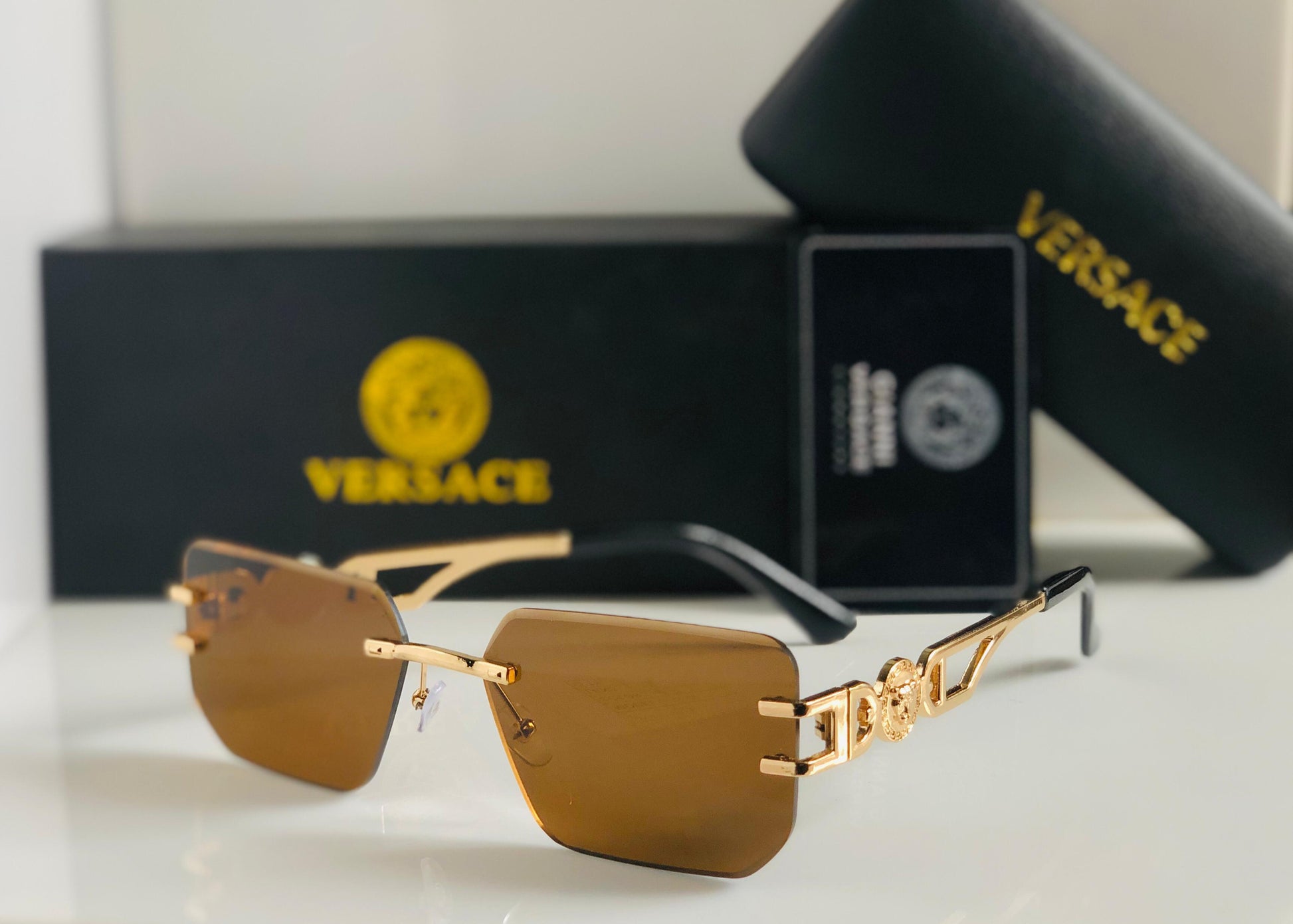 Gold sunglasses with Ver sace packaging in the background