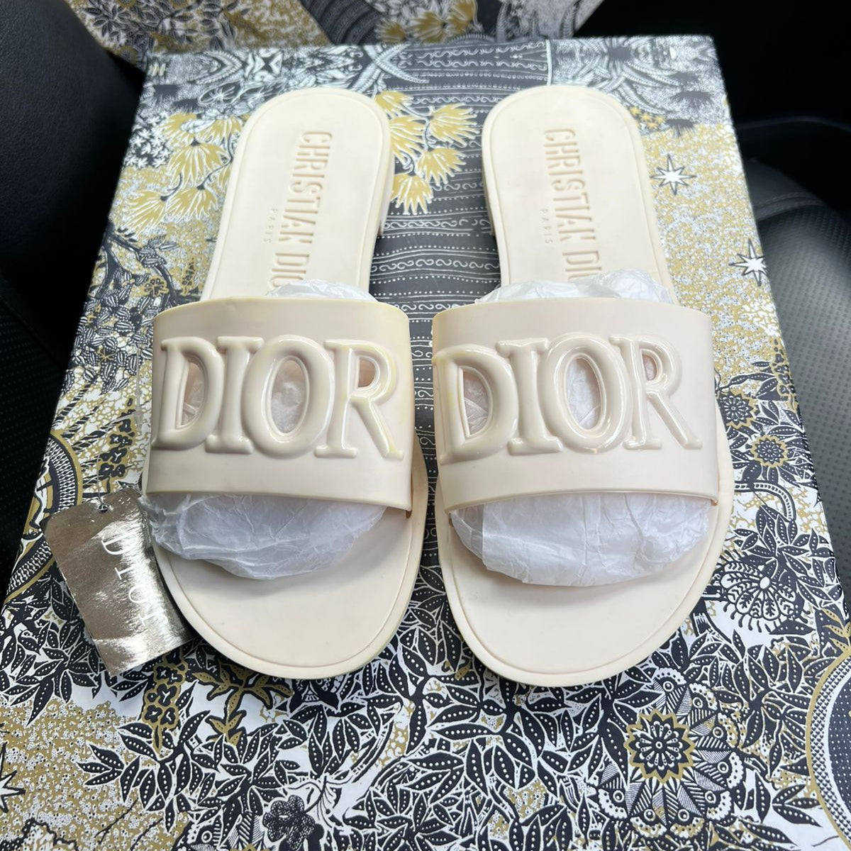 Pair of Dior slides on a patterned surface
