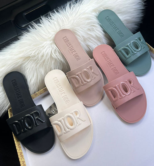 Set of Dior slides in various colors on a fluffy white surface.