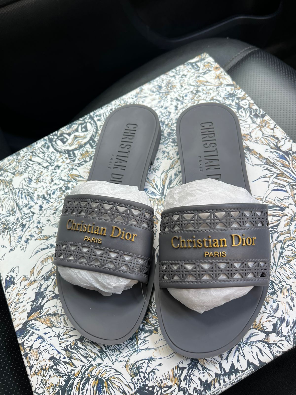 Pair of Christian Dior slides on a patterned surface