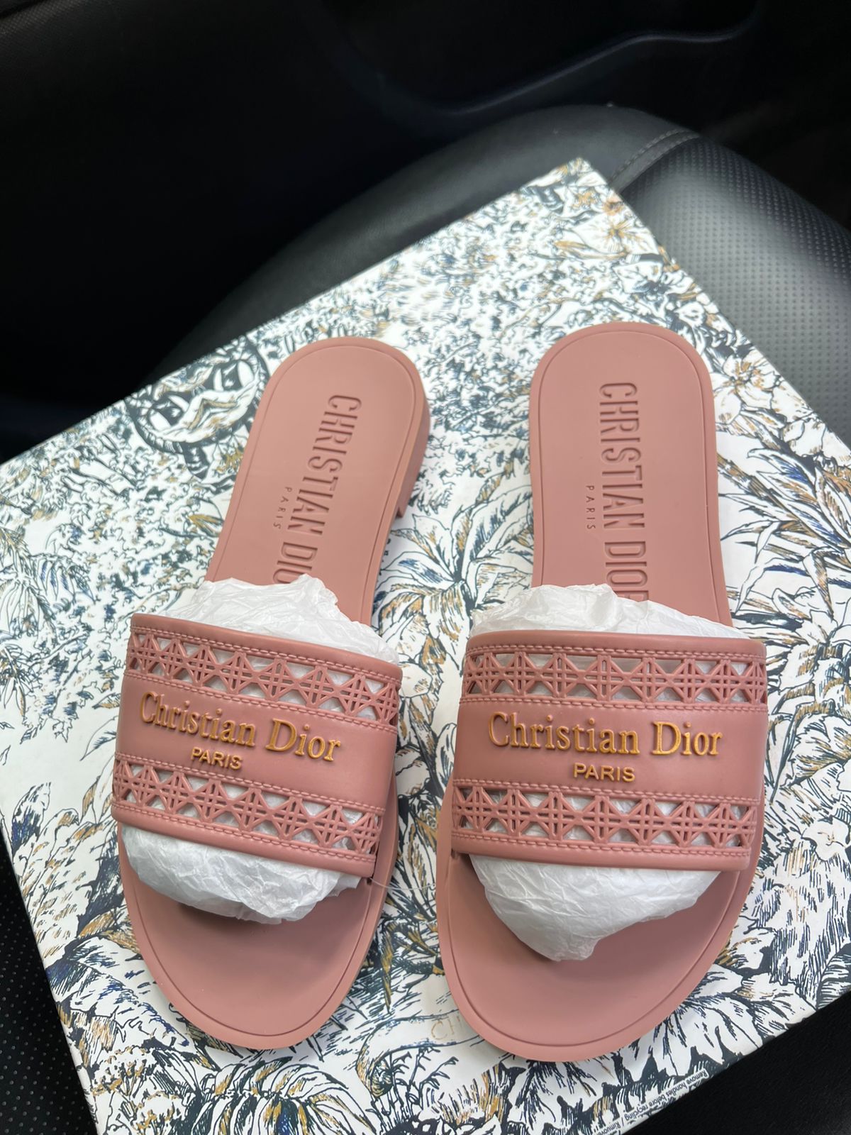Pink Christian Dior slides on a patterned surface