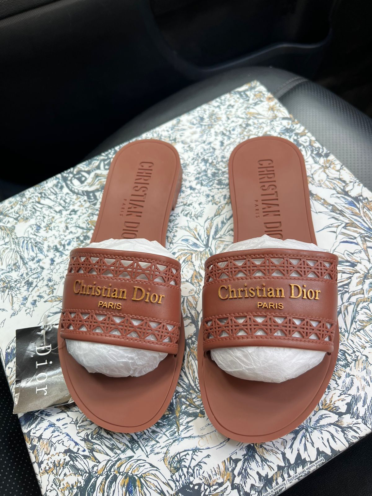 Pair of Christian Dior slides on a patterned surface