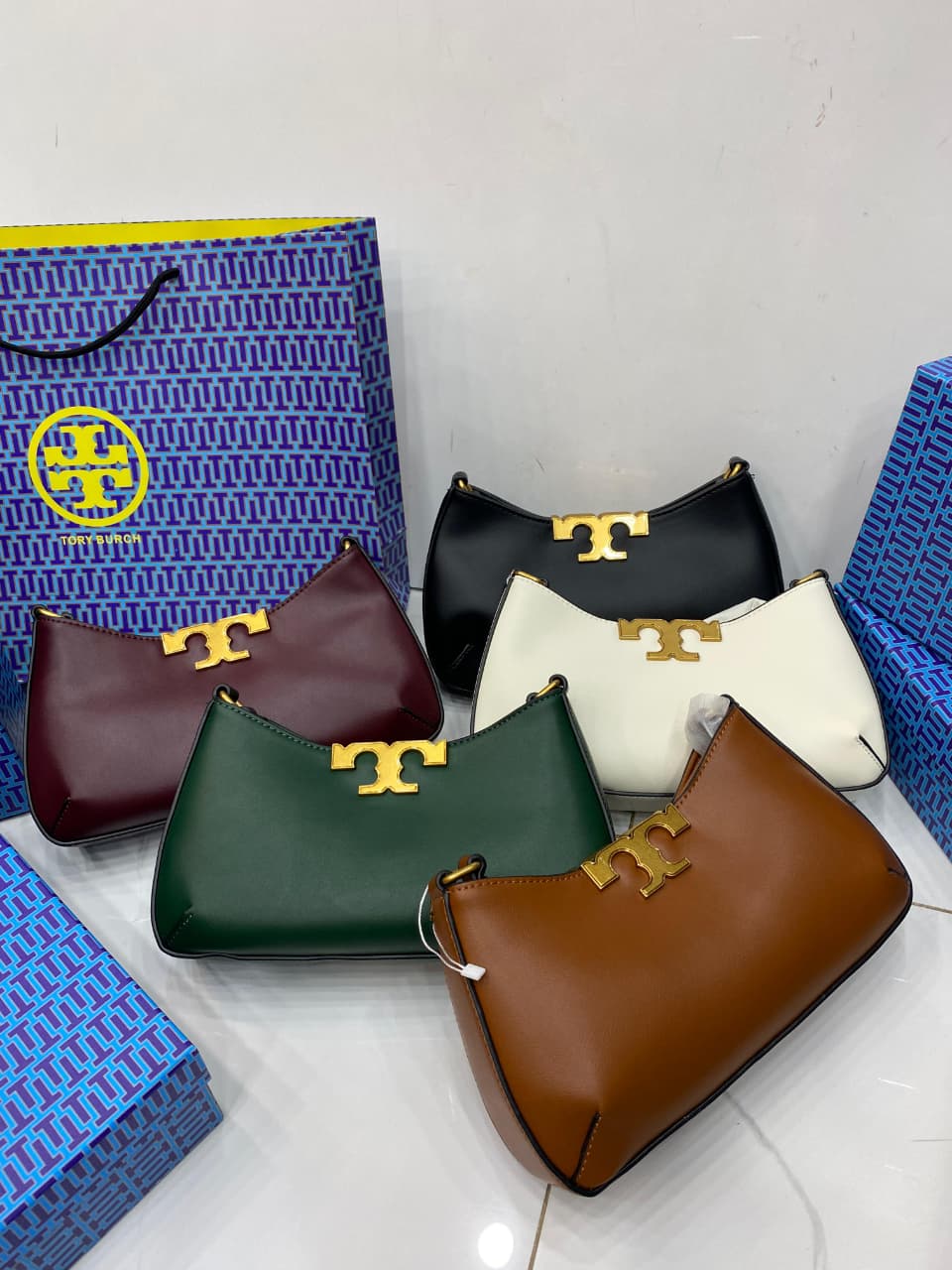 Collection of handbags in various colors with a visible brand logo on a white background