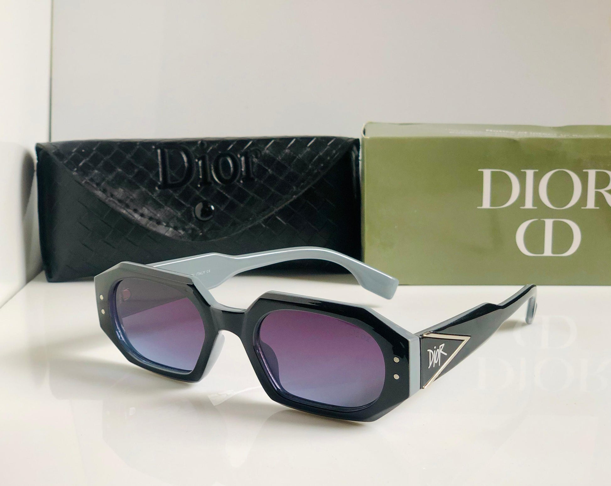 Di or sunglasses with a black case and green box on a white background