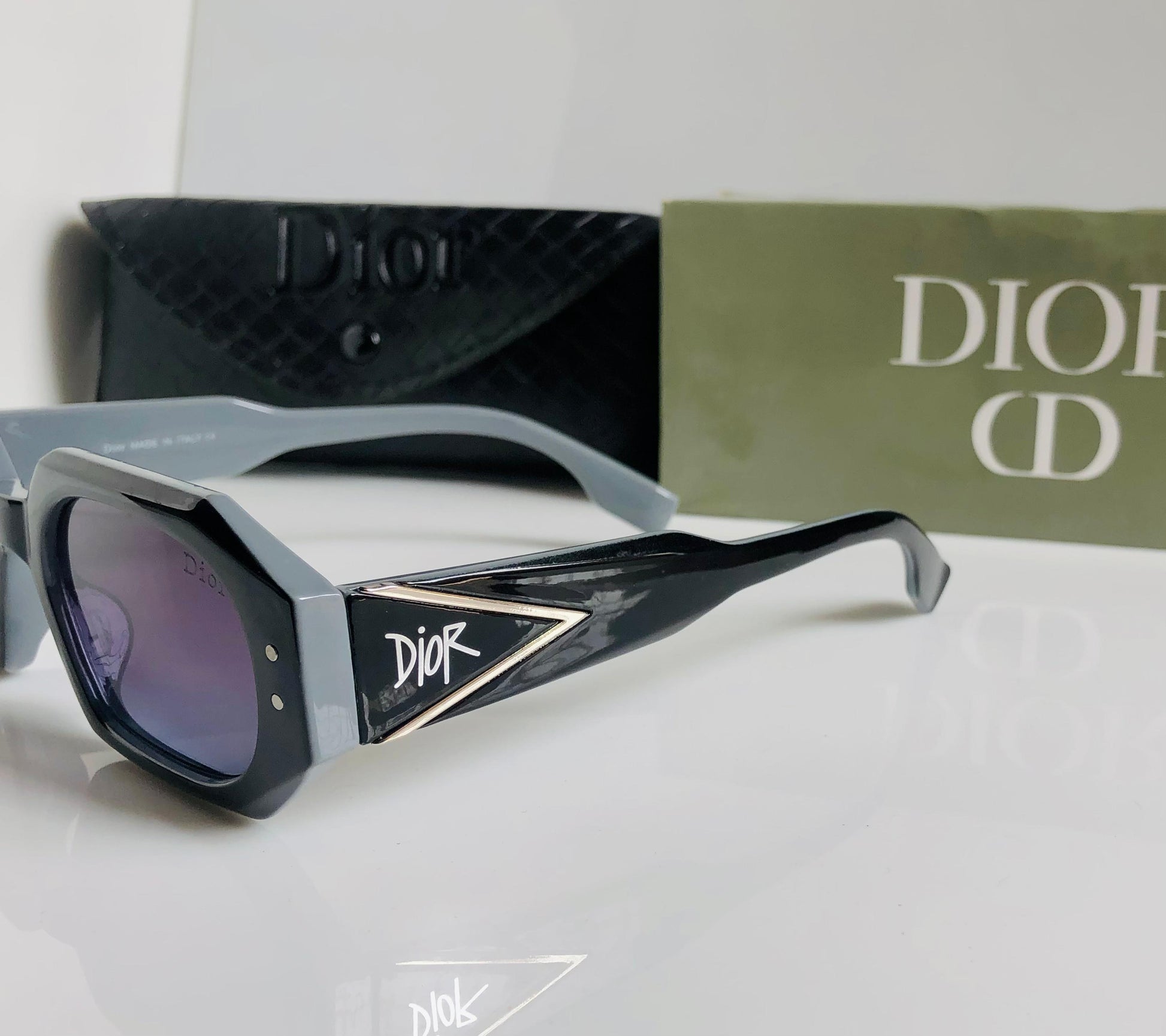 Di or sunglasses with a black and gray frame on a white surface, with Di or branding visible.