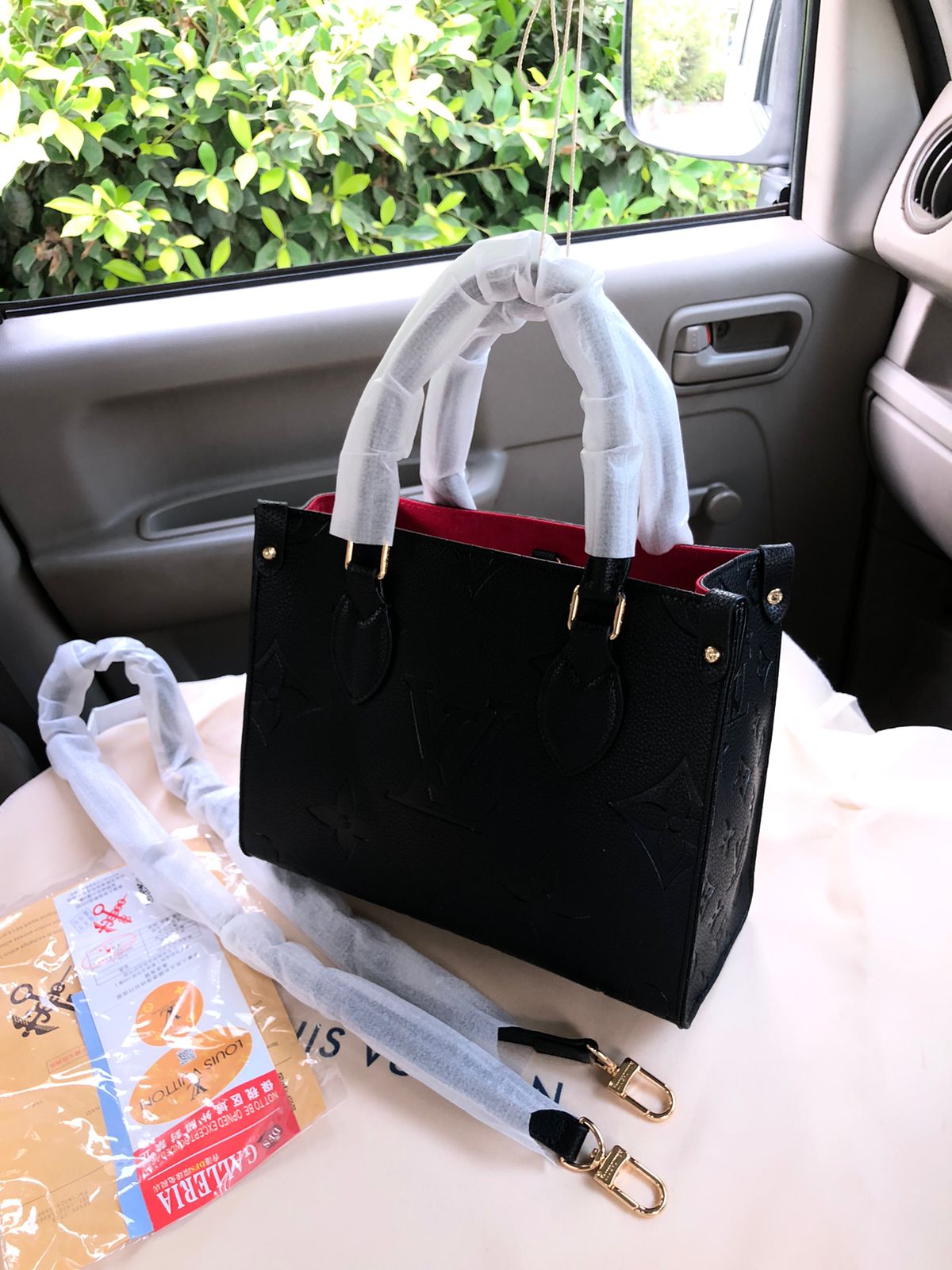Black handbag with white handles and strap on a car seat