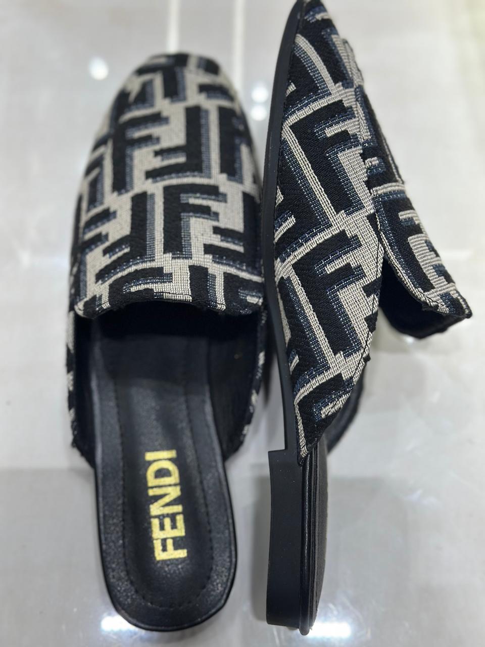 Black and white patterned slides with 'Fendi' logo on a reflective surface